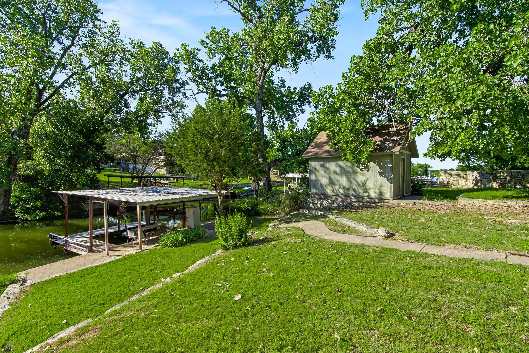 White-sided residence featuring a rock foundation, dark-trimmed windows, and a gravel driveway