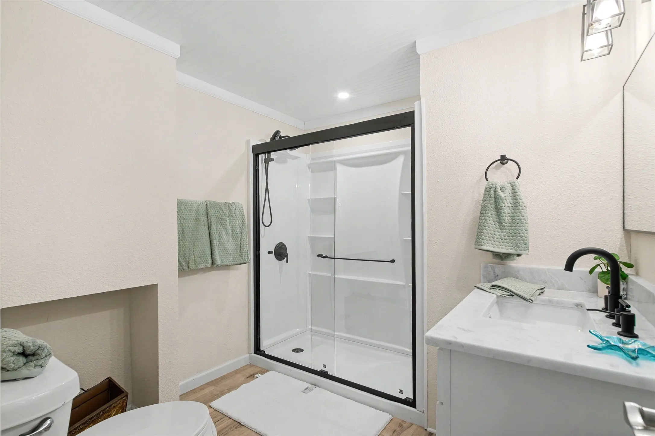Shower with black-framed glass enclosure, white basin, and matte black fixtures