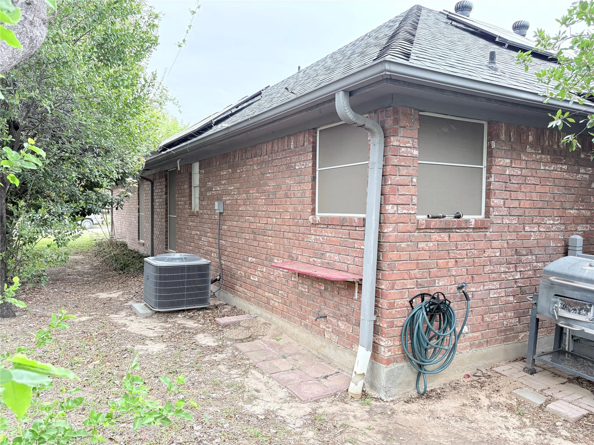 View of property exterior featuring brick siding and roof with shingles