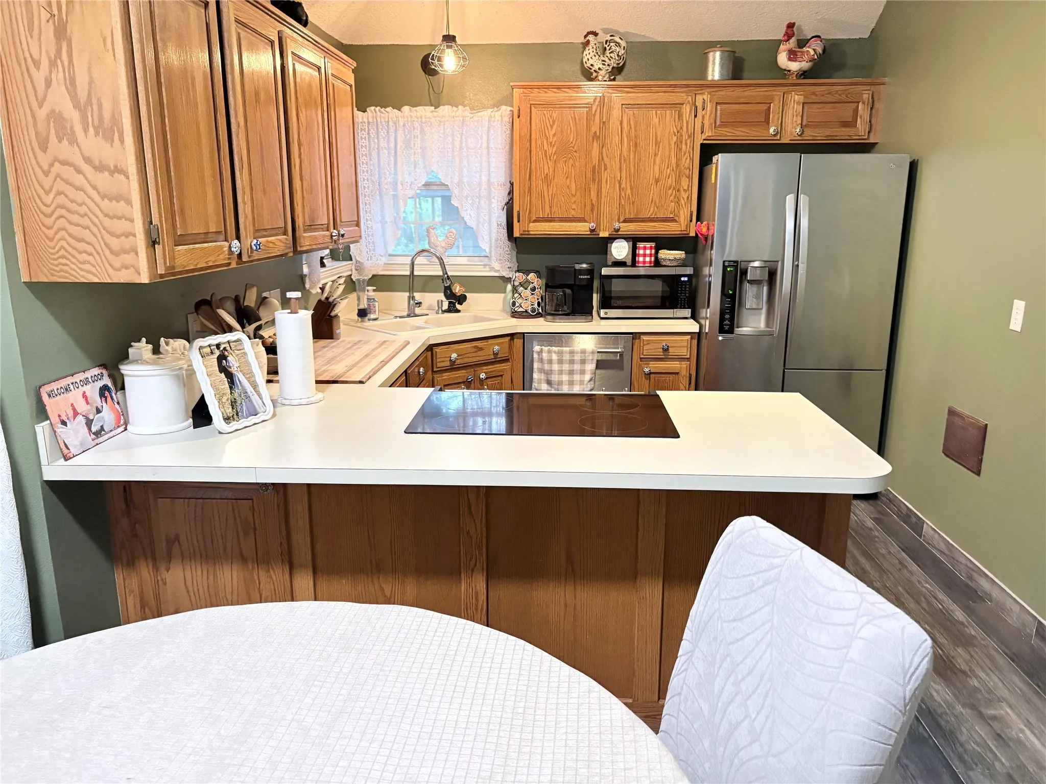 Kitchen featuring light countertops, stainless steel appliances, wood finish cabinetry, and dark wood-style flooring