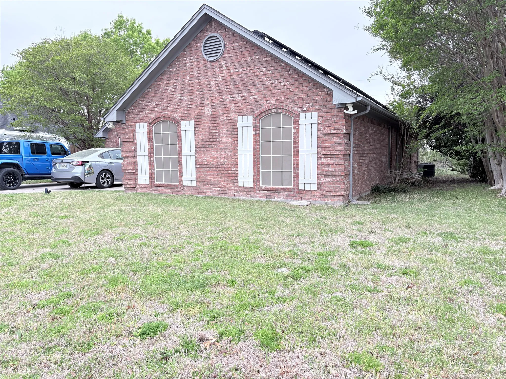 View of home's exterior with brick siding and a lawn