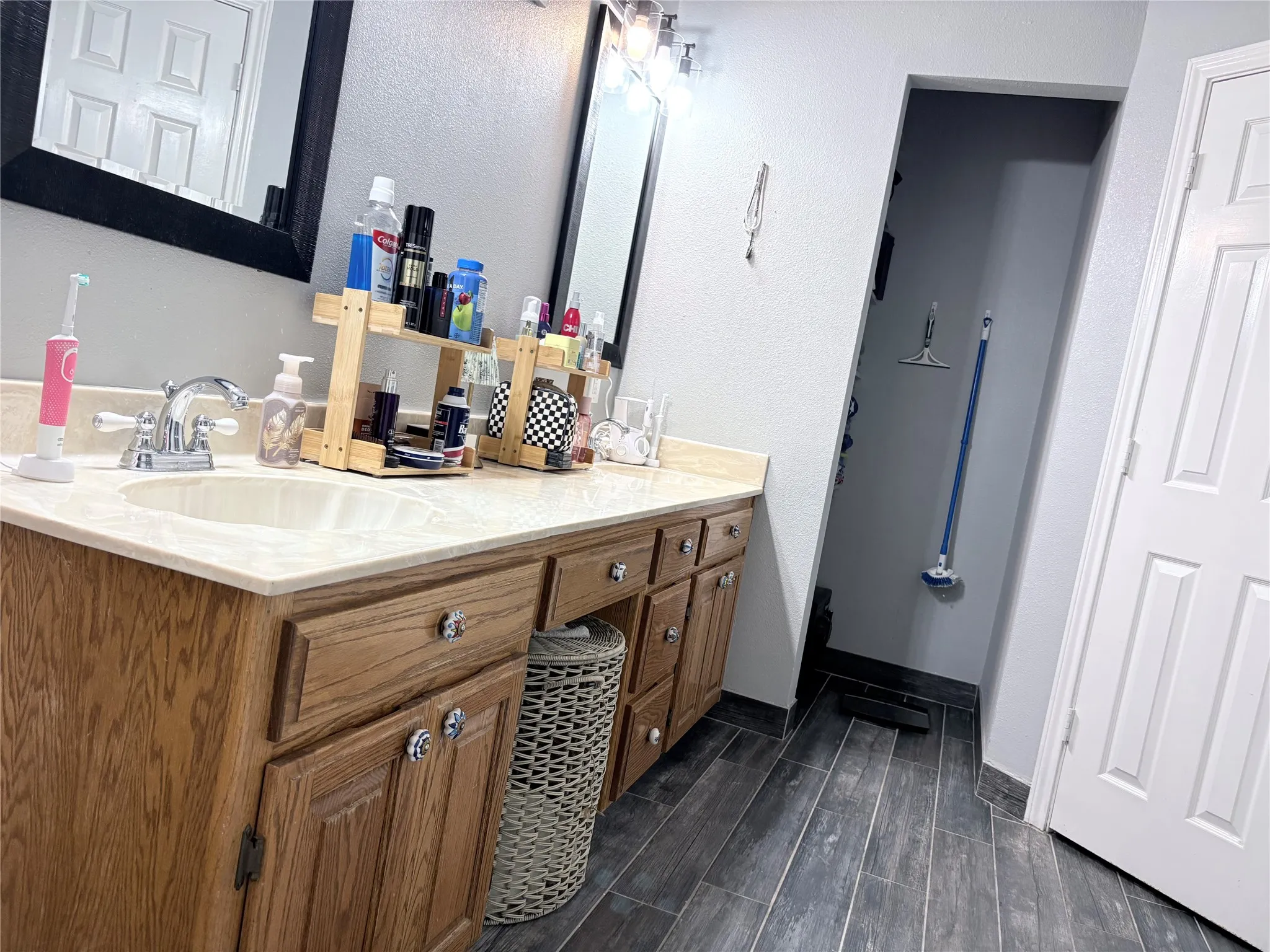 Bathroom featuring double vanity, wood finish floors, and a textured wall