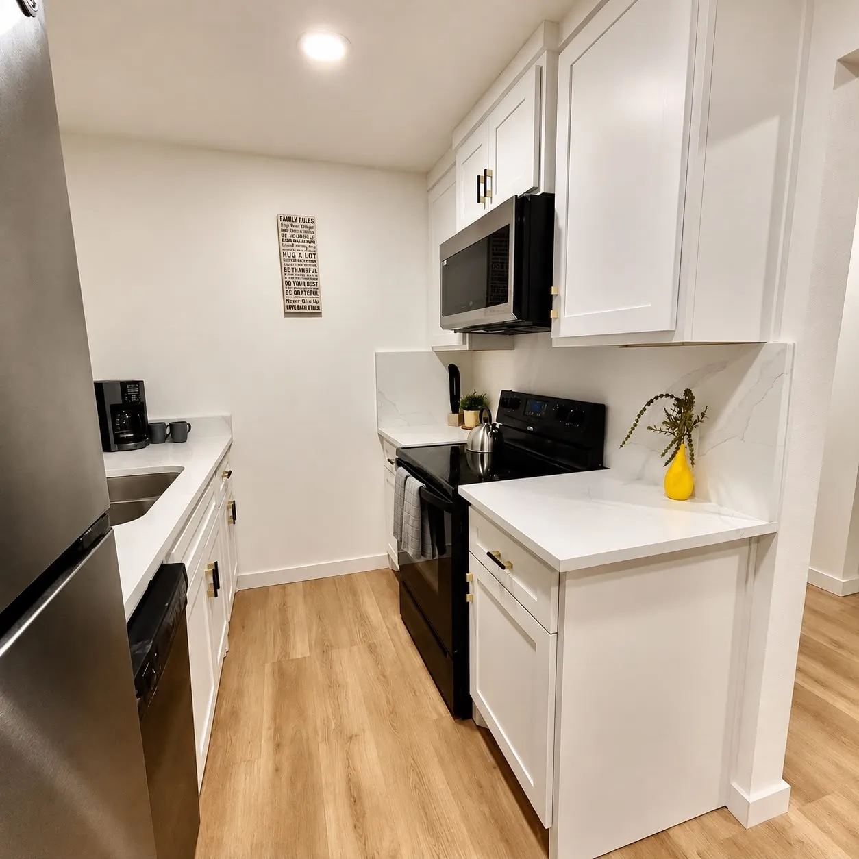 White cabinetry, wood-finish flooring, stainless steel appliances, white countertops, and recessed lighting
