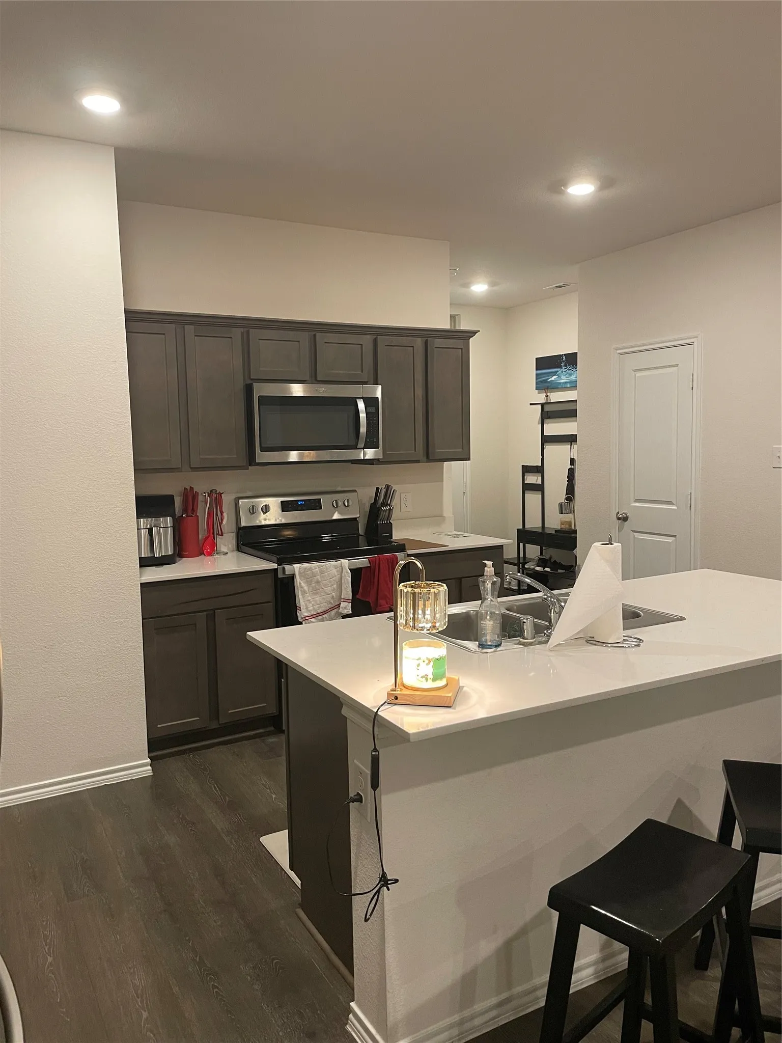 Kitchen with a breakfast bar area, stainless steel appliances, dark wood finished floors, a kitchen island with sink, and recessed lighting