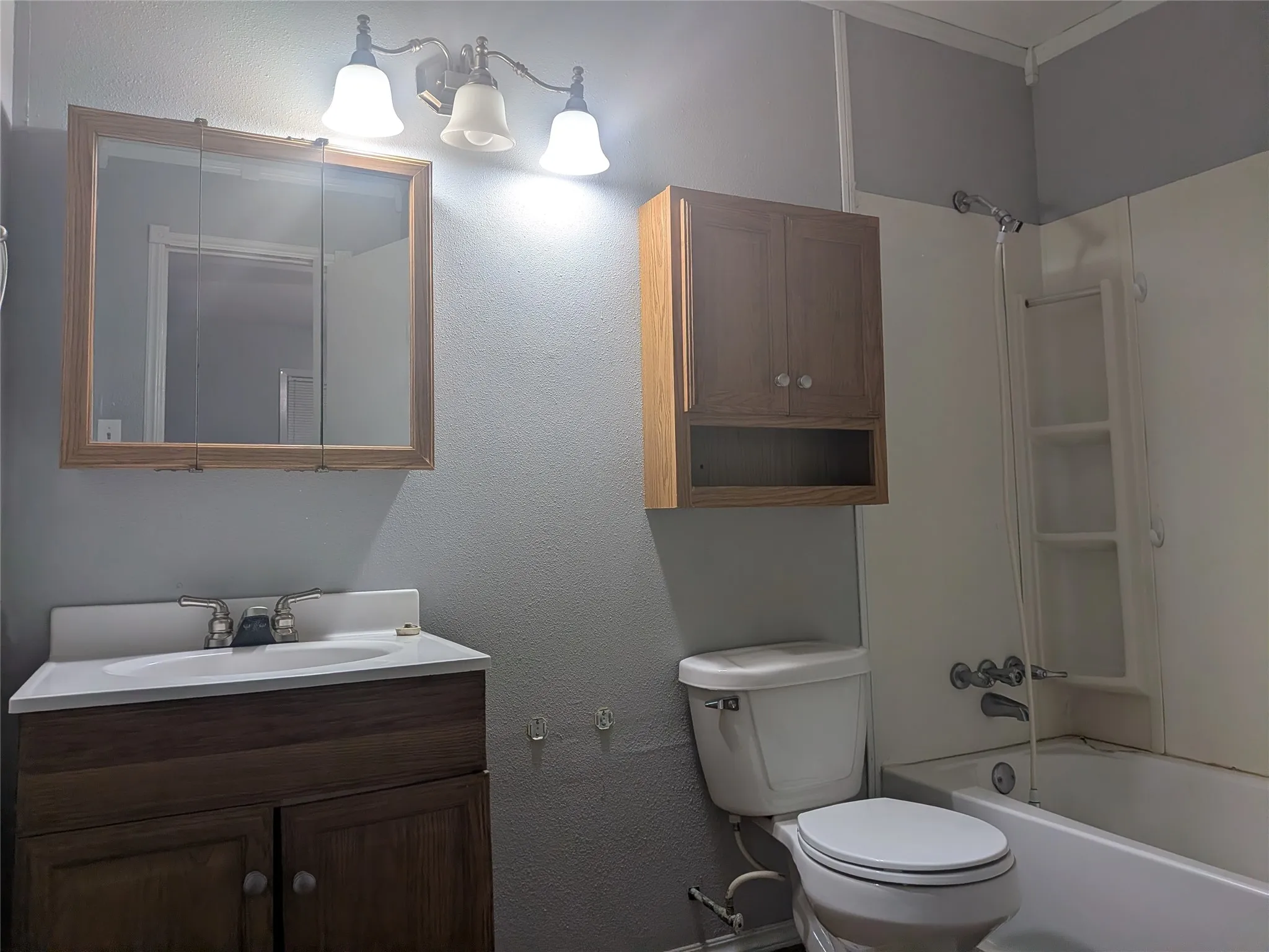 Bathroom featuring vanity, shower / bath combination, and a textured wall
