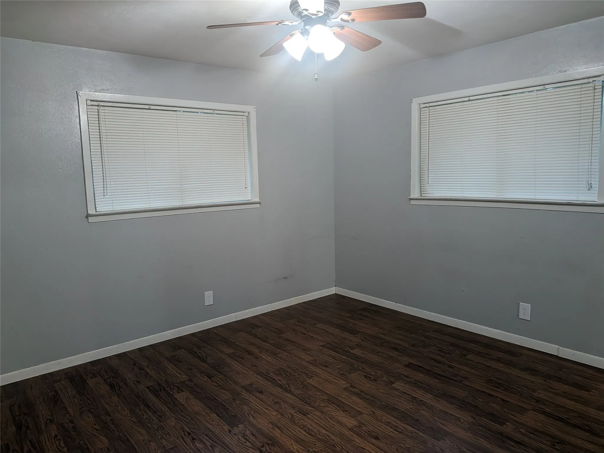 Unfurnished room featuring ceiling fan and dark wood-style flooring