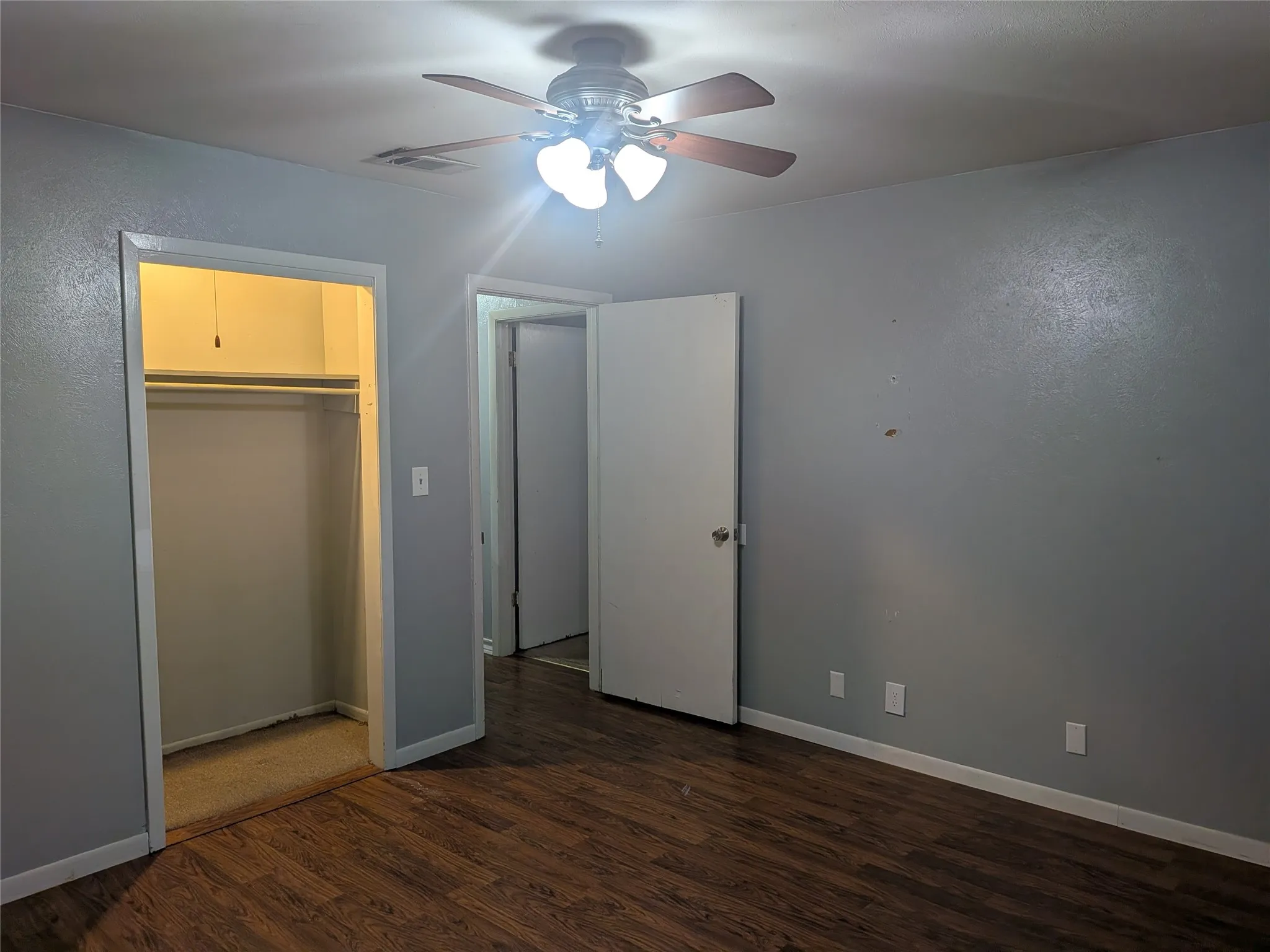 Unfurnished bedroom featuring dark wood-type flooring, a ceiling fan, and a closet