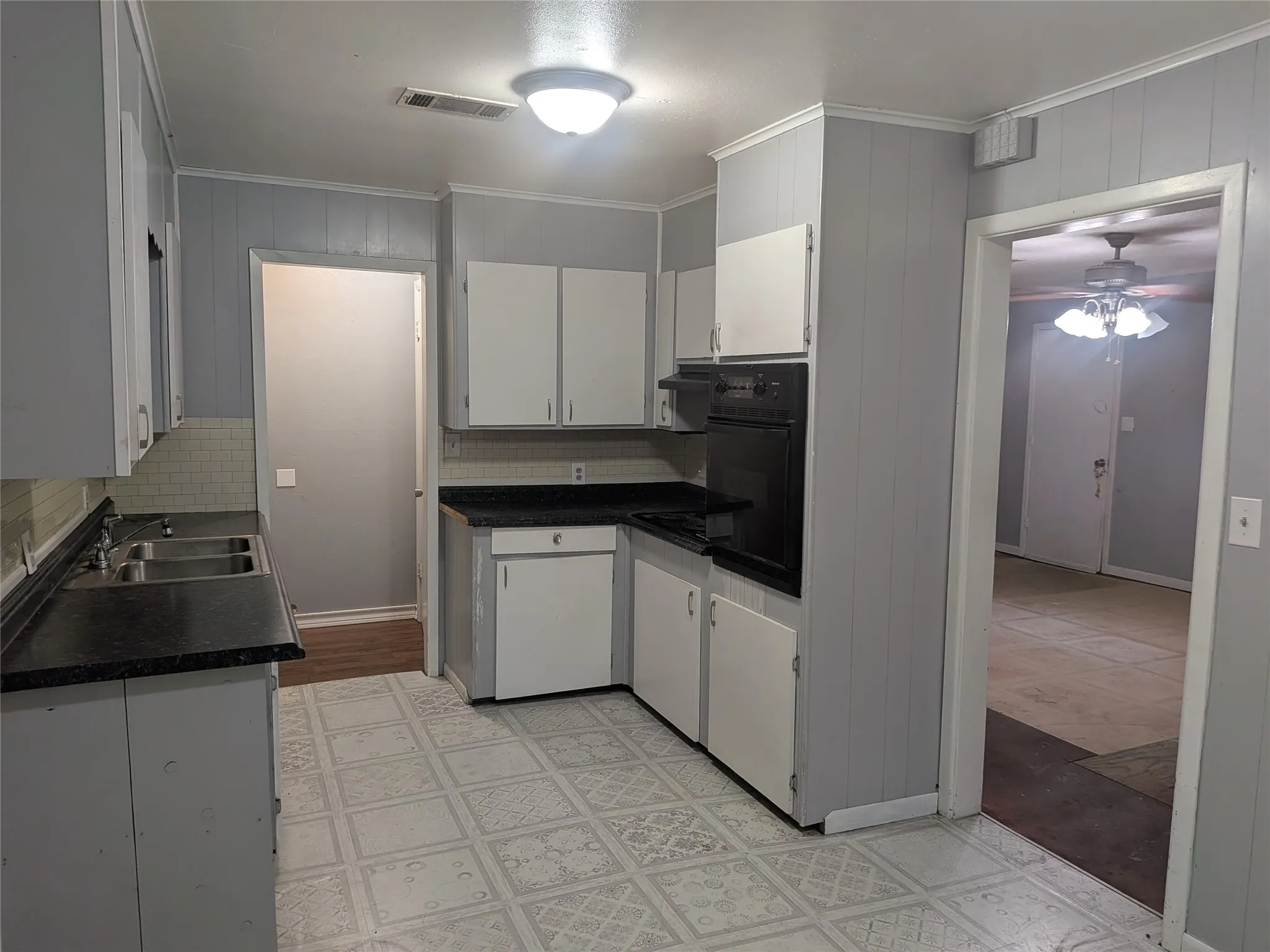 Kitchen featuring white cabinets, dark countertops, oven, ceiling fan, and light flooring