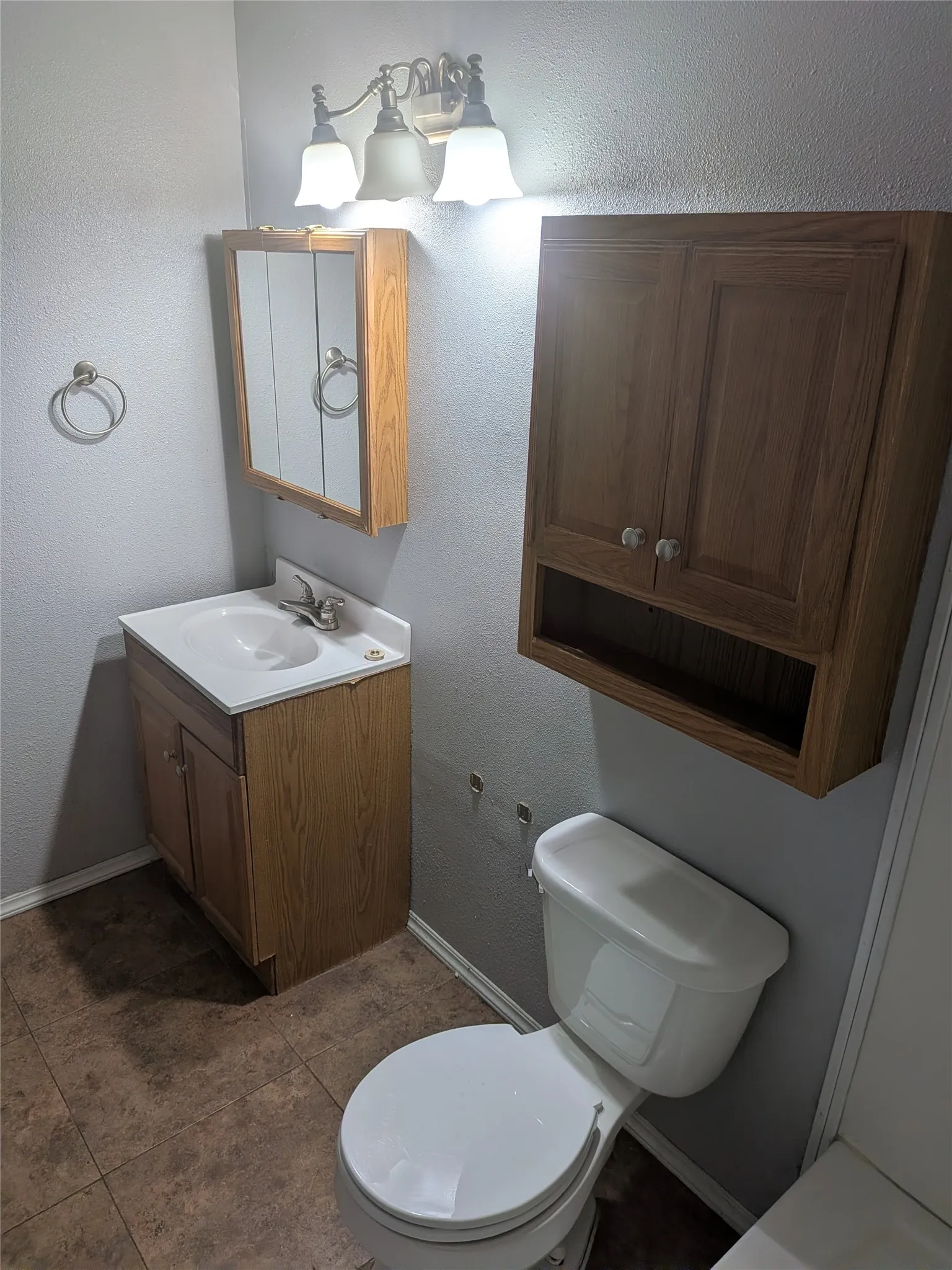Bathroom with vanity, a textured wall, and dark tile patterned floors