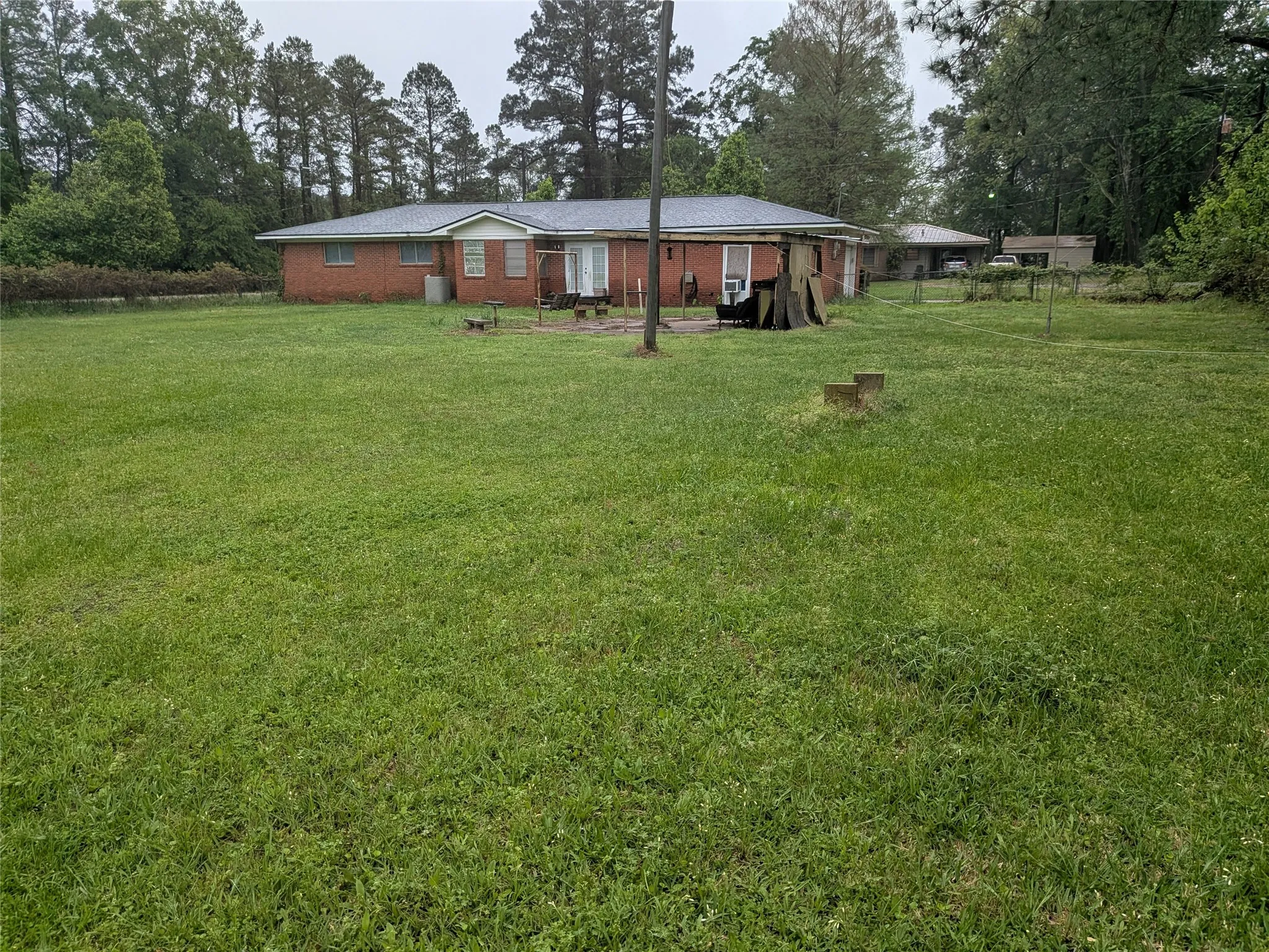 Rear view of property featuring a lawn, view of wooded area, and brick siding