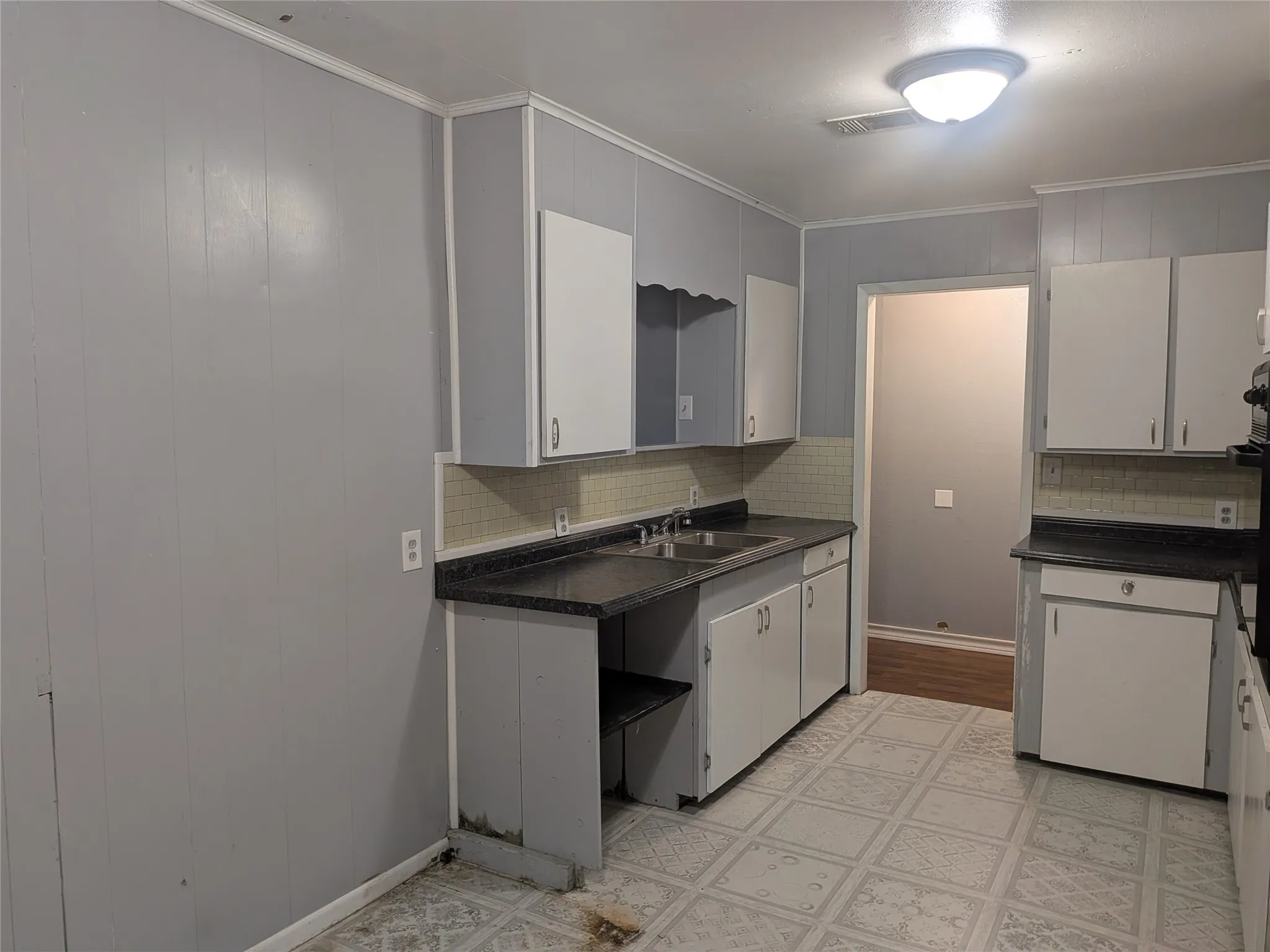 Kitchen featuring dark countertops, tasteful backsplash, ornamental molding, and gray cabinetry