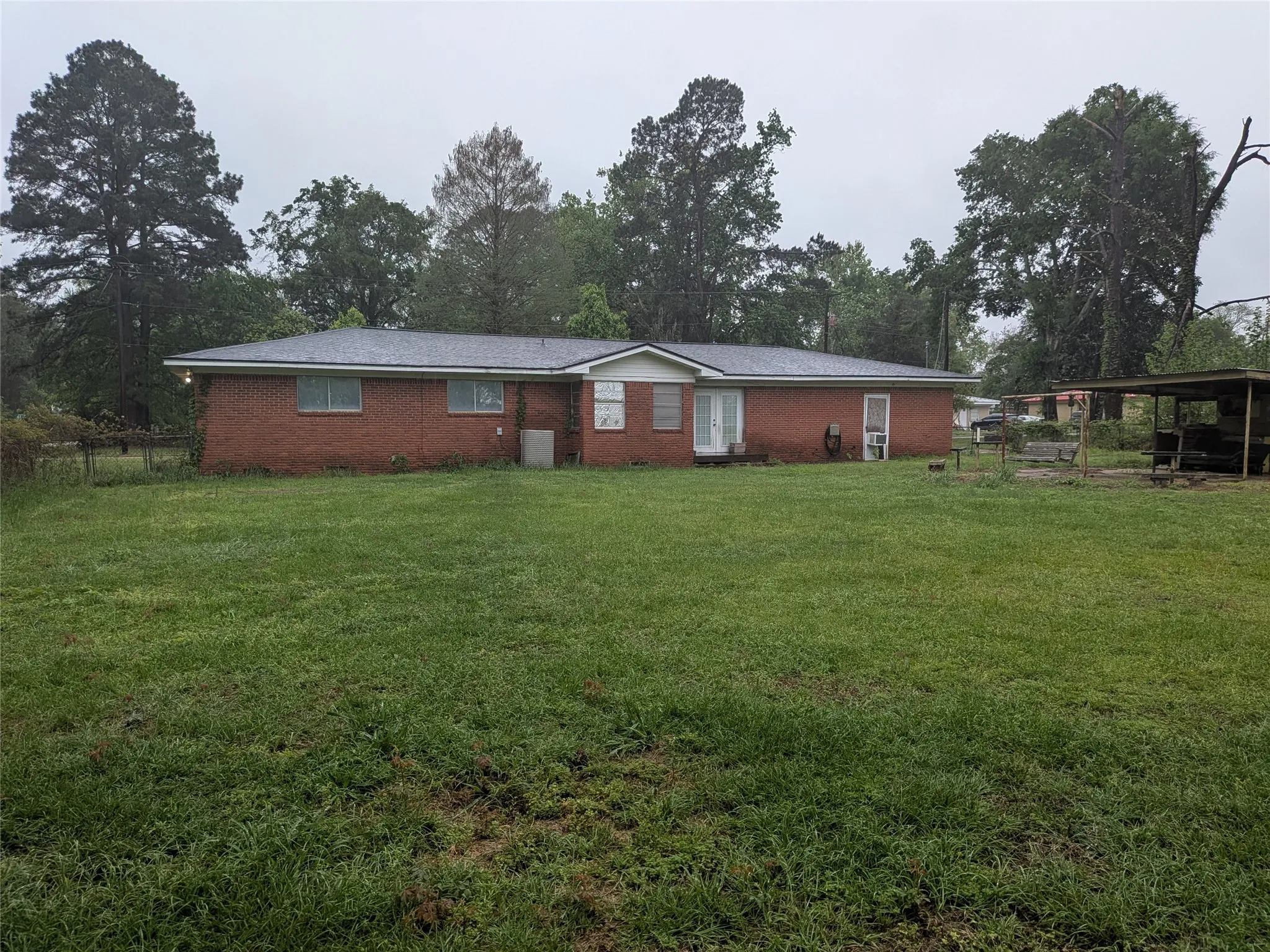View of front of property with brick siding and view of wooded area