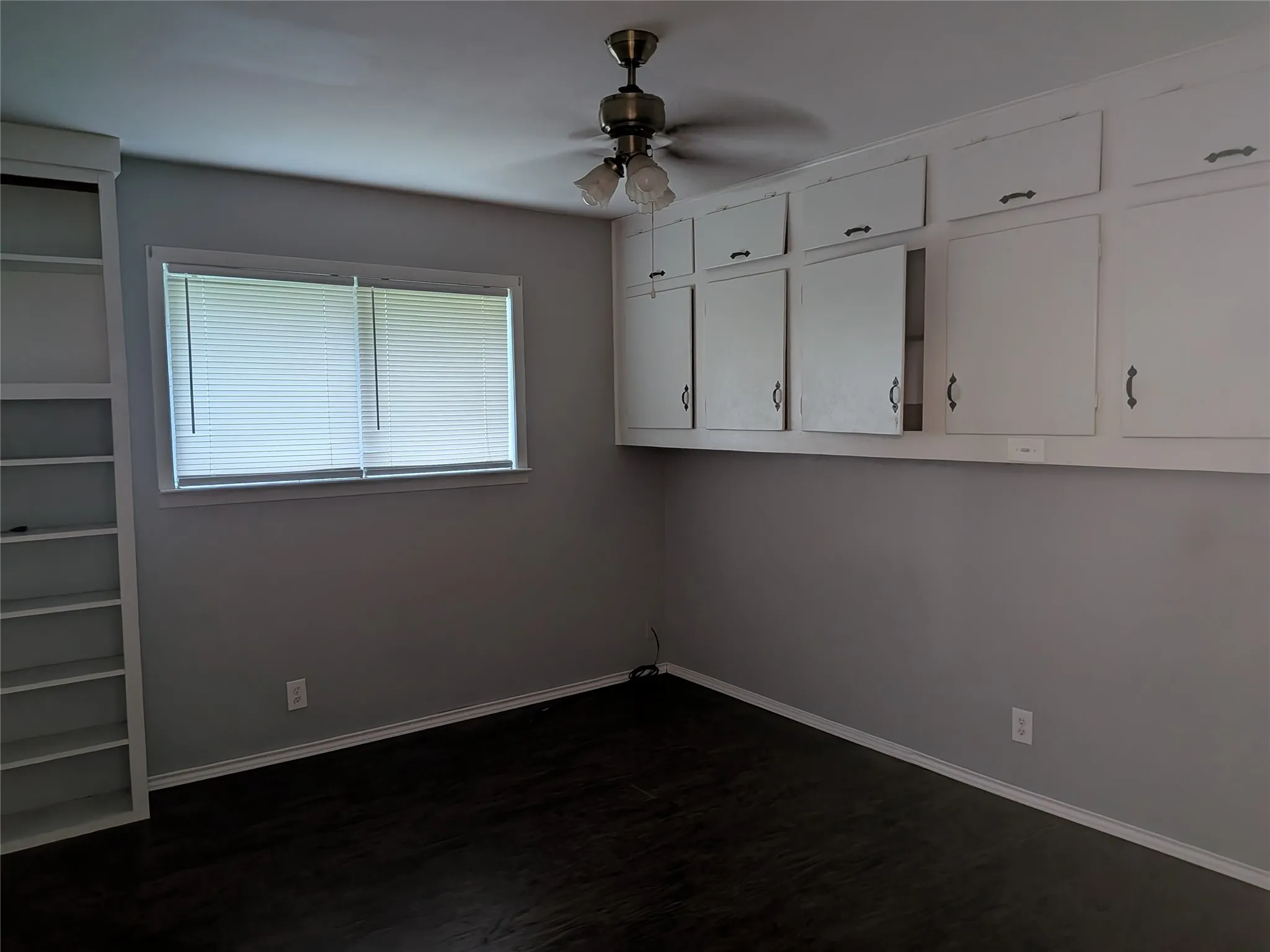 Unfurnished room featuring a ceiling fan and dark wood-type flooring