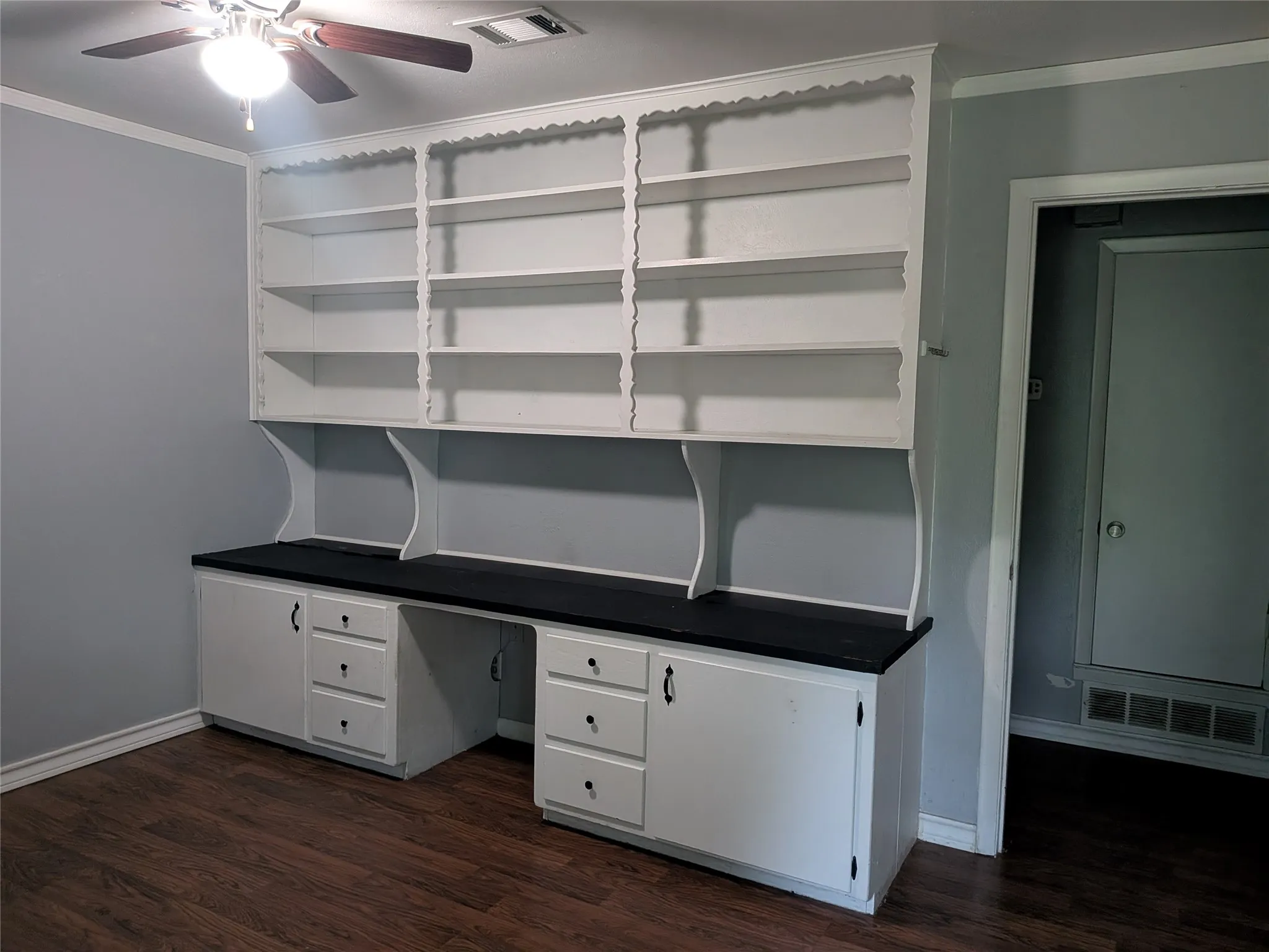 Unfurnished office featuring ornamental molding, dark wood-style flooring, a ceiling fan, and built in study area