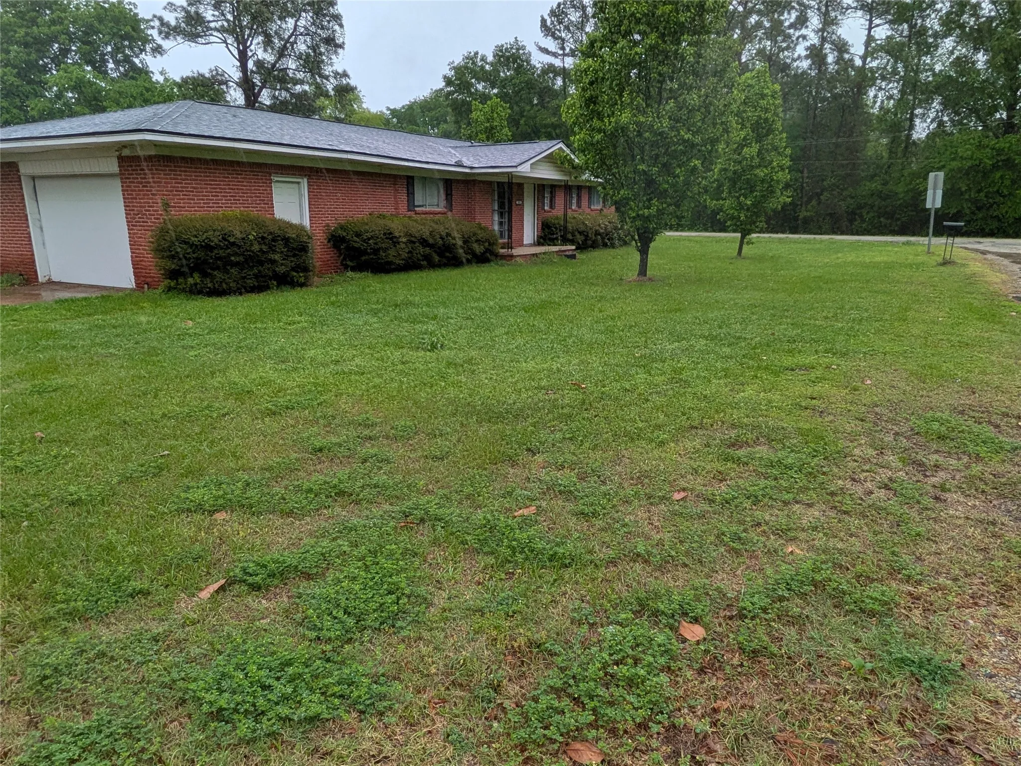 View of front of house featuring a garage, brick siding, and a front lawn