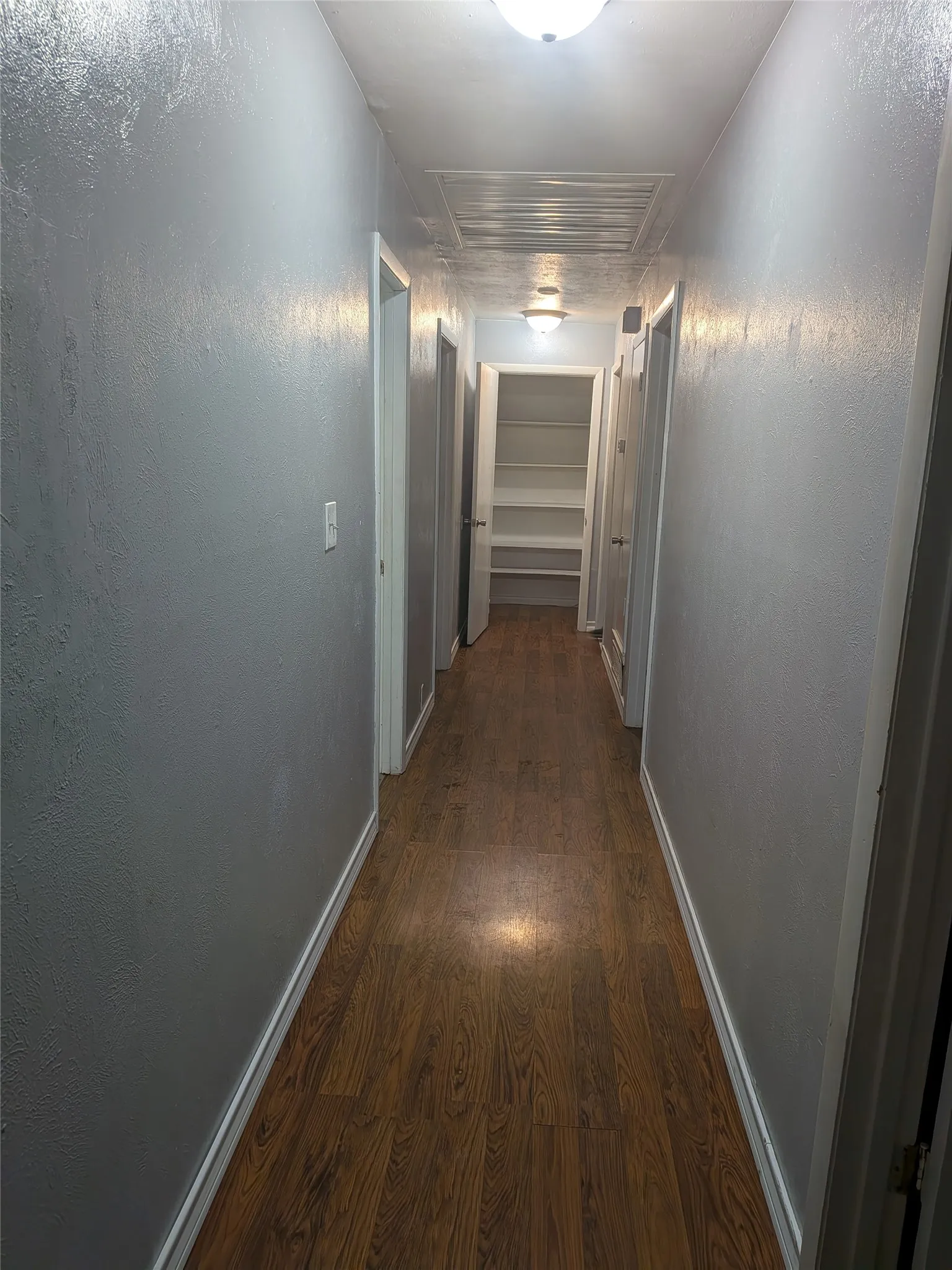 Hall featuring dark wood-style flooring and baseboards