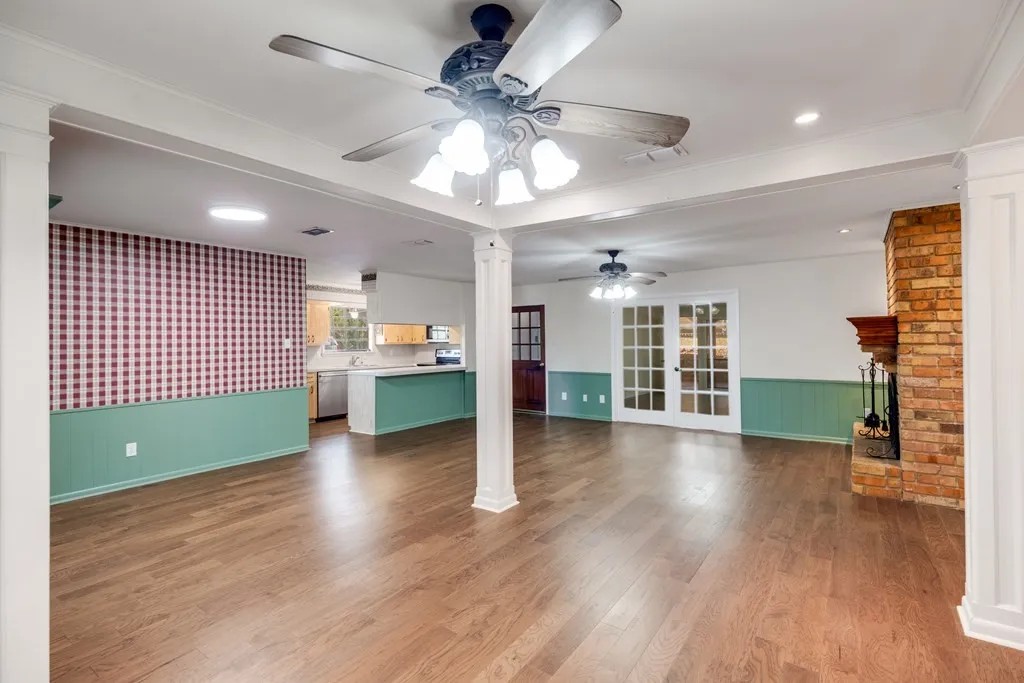 Unfurnished living room featuring decorative columns, a wainscoted wall, wallpapered walls, dark wood-style flooring, and recessed lighting