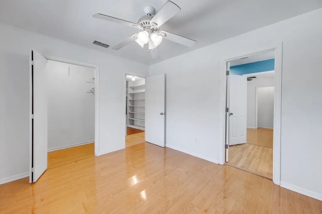 Unfurnished bedroom featuring a spacious closet, a ceiling fan, and light wood-style flooring