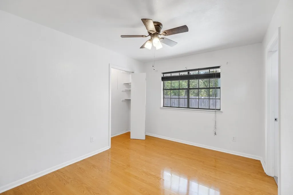 Unfurnished bedroom featuring a spacious closet, light wood-style flooring, and a ceiling fan
