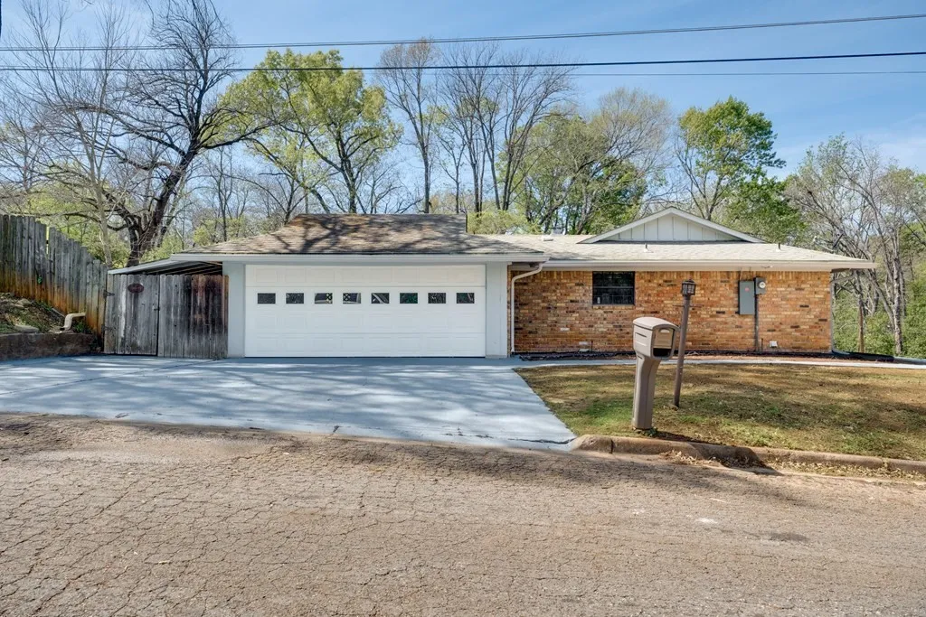 Ranch-style house with brick siding, a garage, driveway, and roof with shingles