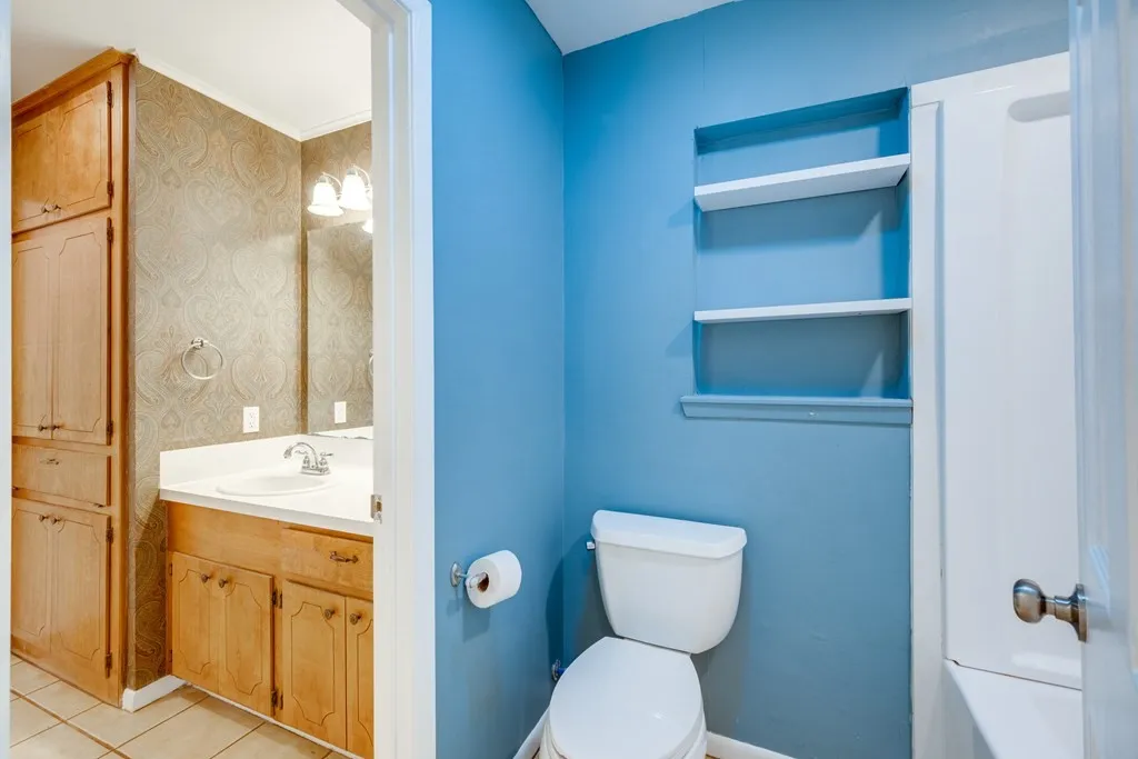 Bathroom with vanity, wallpapered walls, light tile patterned floors, and built in shelves