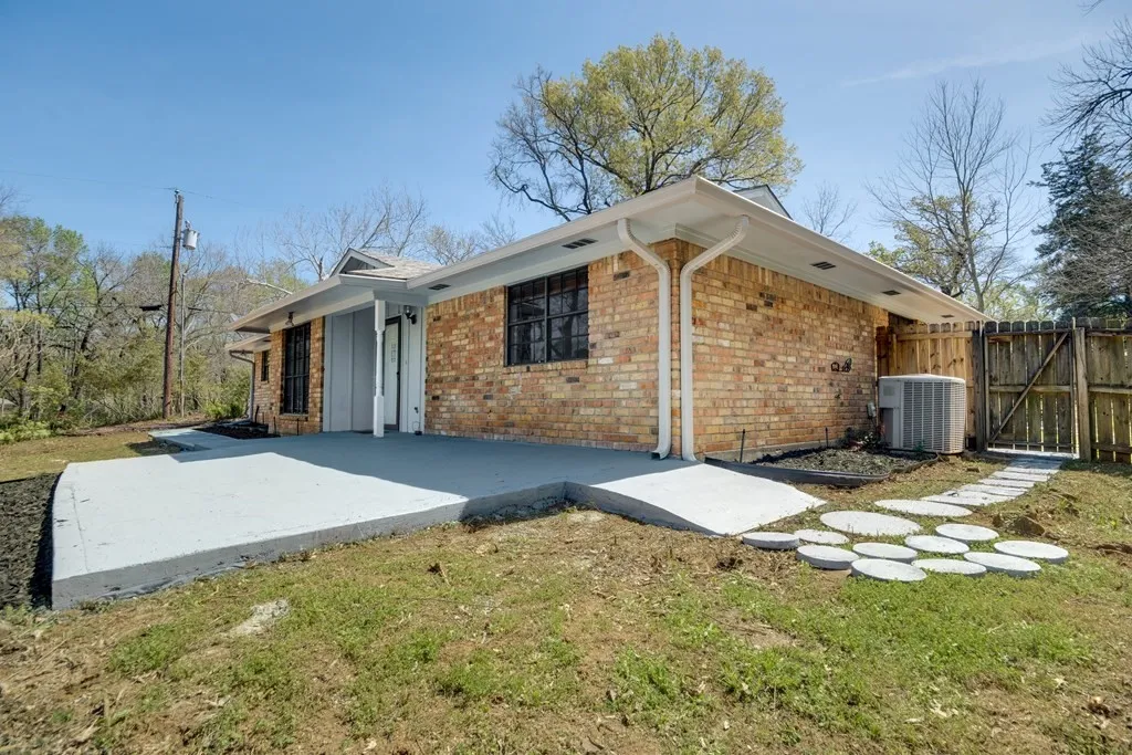 View of side of property with brick siding, a gate, a patio, and a lawn