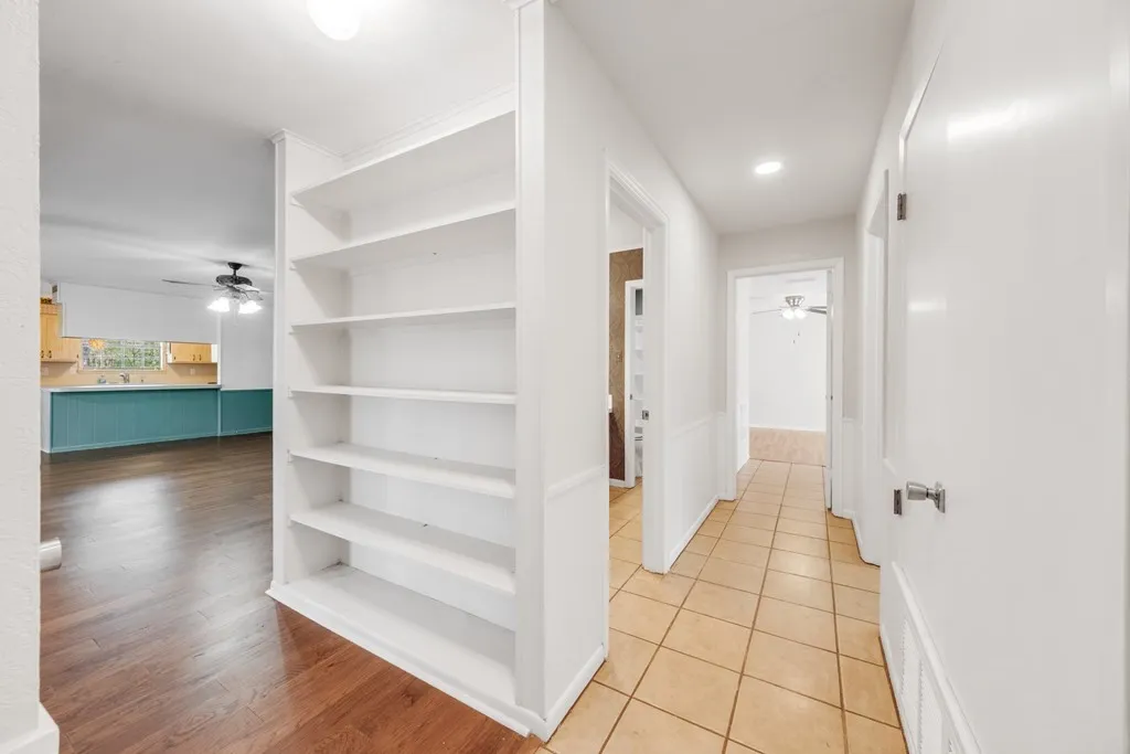 Corridor featuring built in shelves and light tile patterned floors