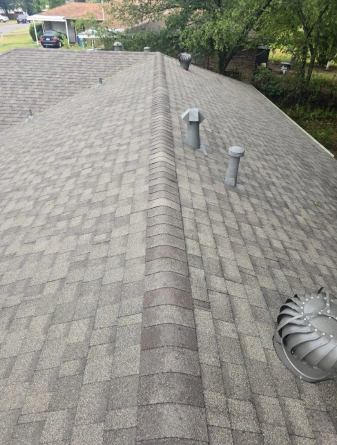 Asphalt shingle roofing with a ridgeline, multiple ventilation pipes, and a roof turbine