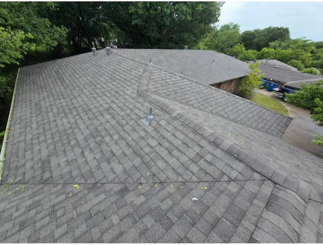 Asphalt shingle roofing system featuring multiple roof planes, ridge caps, and visible guttering