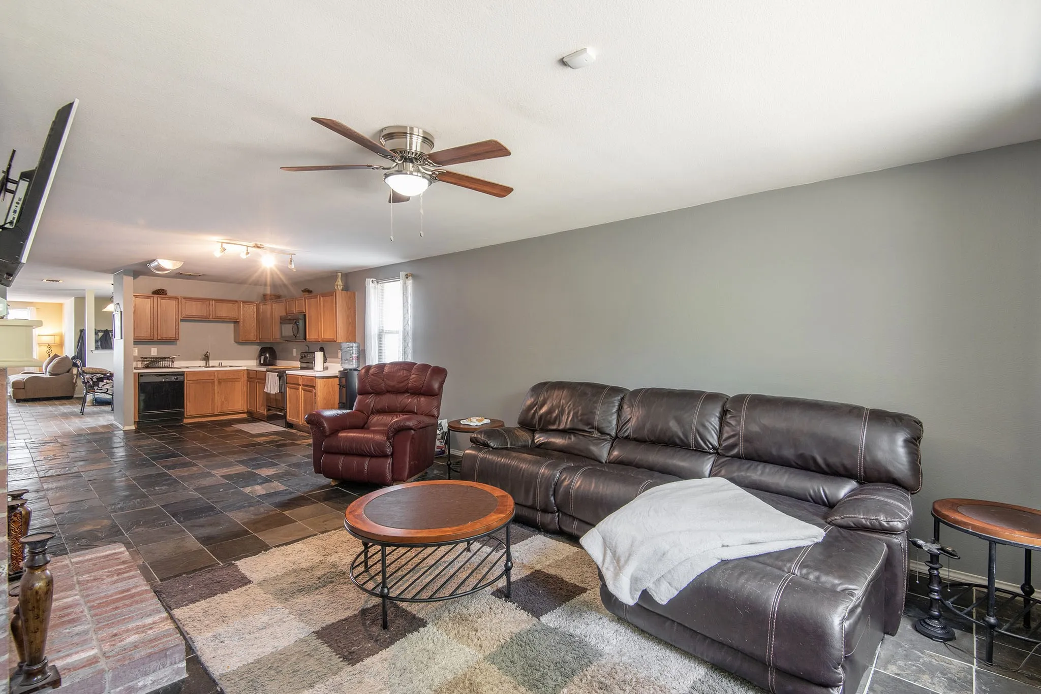 Living room featuring stone tile flooring and ceiling fan