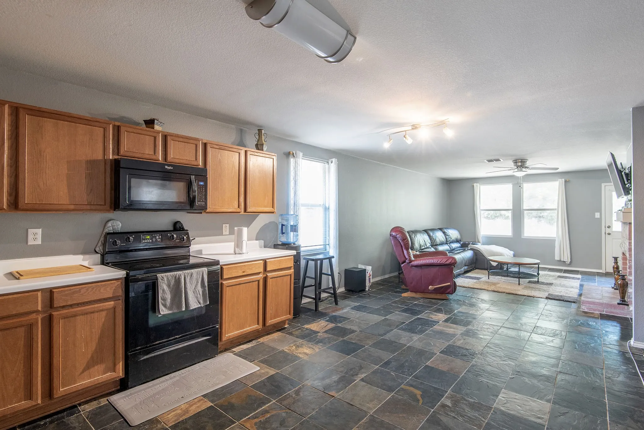 Kitchen featuring black appliances, light countertops, open floor plan, and dark stone finish floors