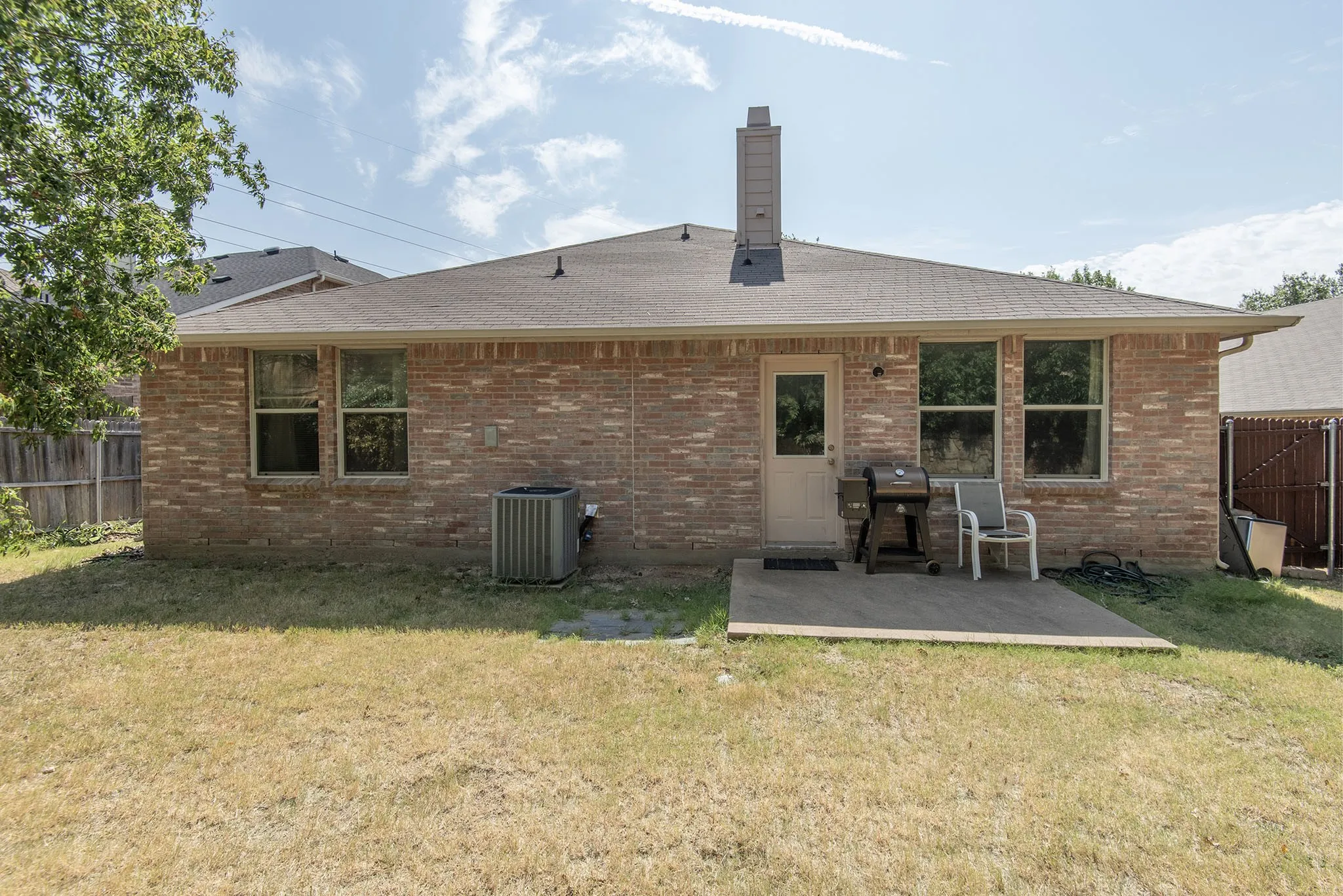 Rear view of property with a fenced backyard, brick siding, and a chimney