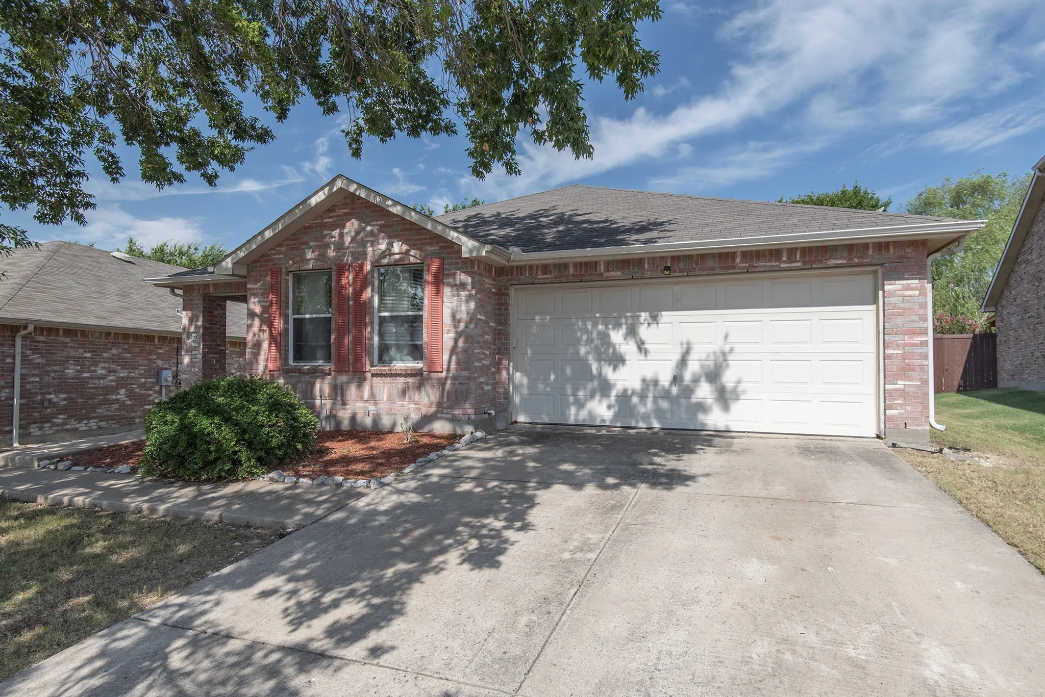 Ranch-style home with concrete driveway, a garage, brick siding, and roof with shingles