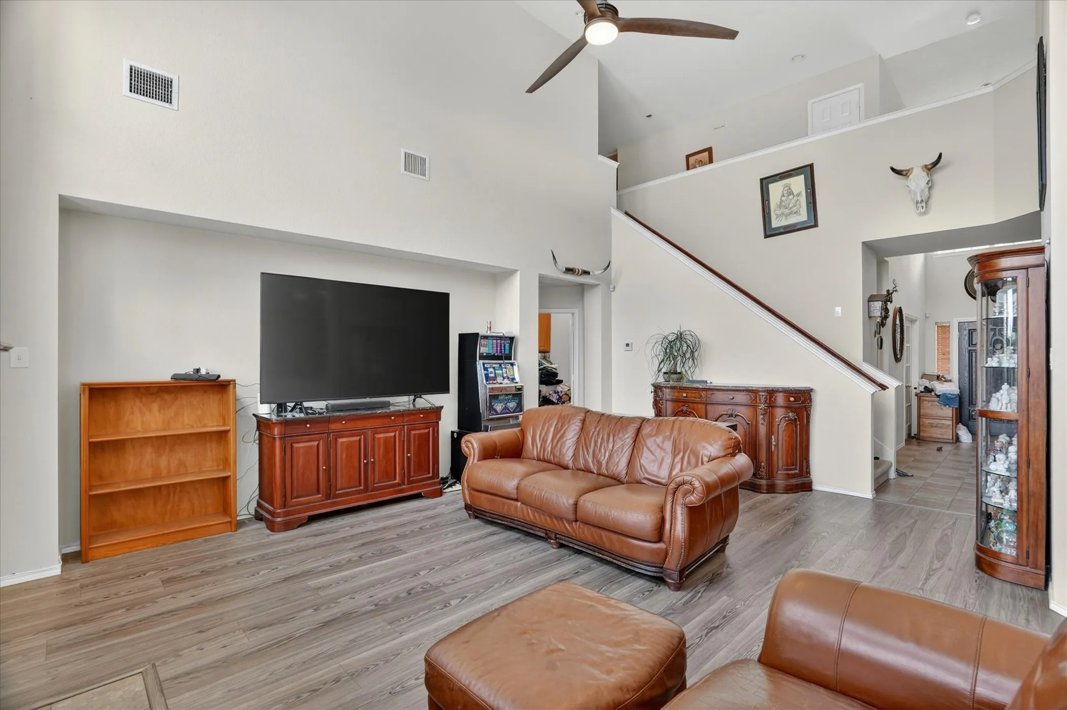 Spacious living area featuring vaulted ceilings, wood-finish flooring, a ceiling fan, and staircase access to an upper level