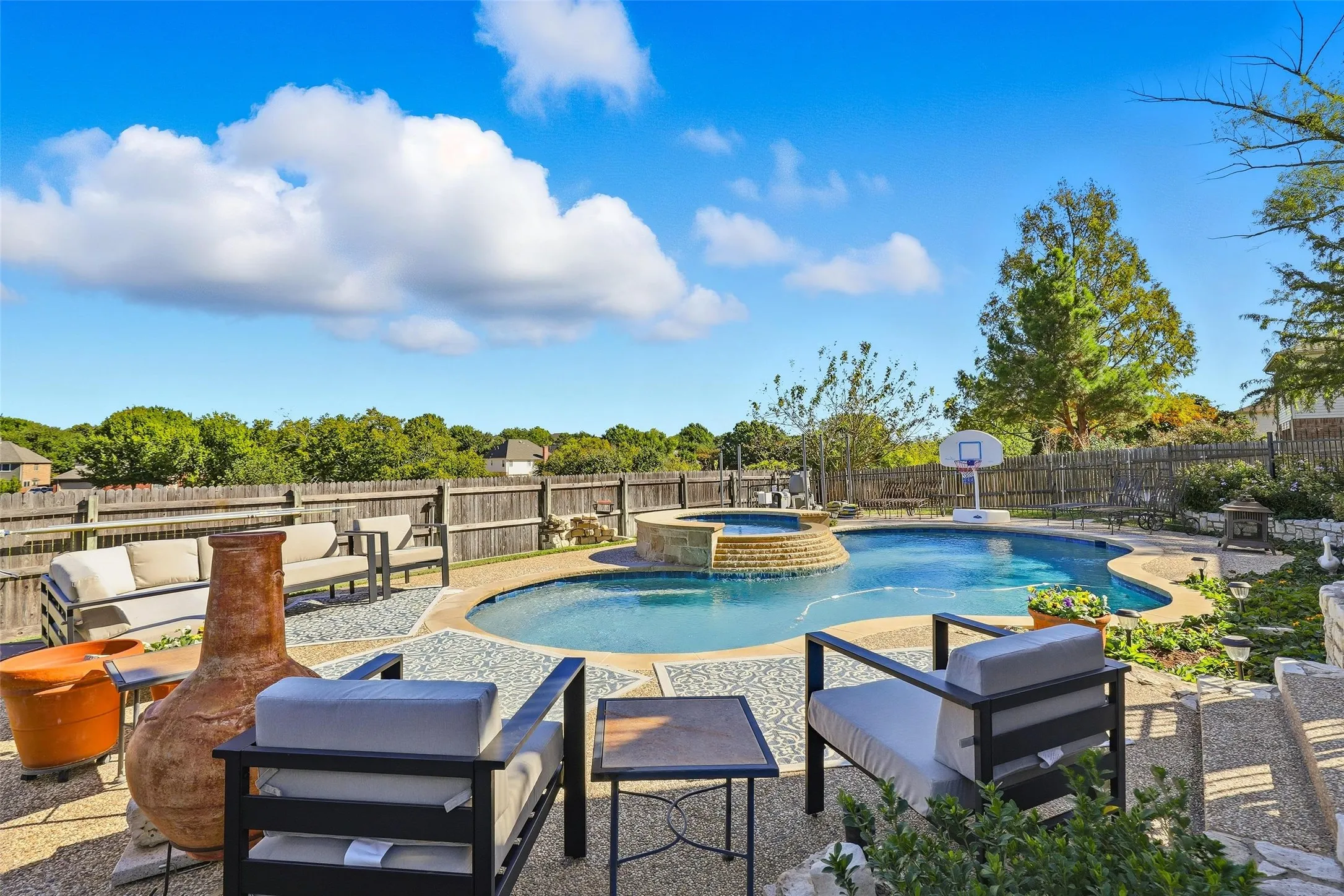 Integrated pool / spa with a patio area, an outdoor hangout area, and a fenced backyard