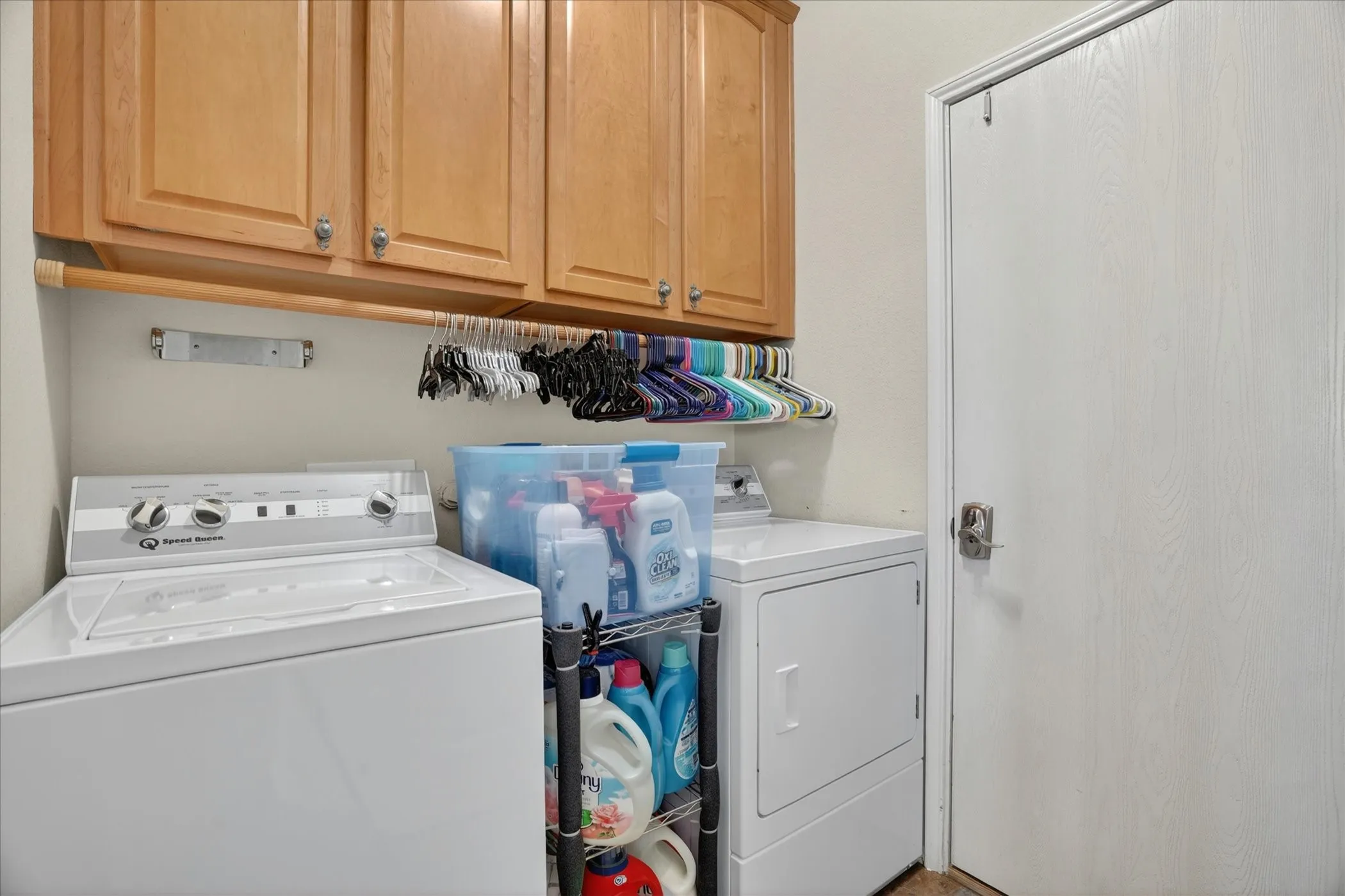 Laundry area featuring light wood cabinetry, a hanging rod, and a white interior door