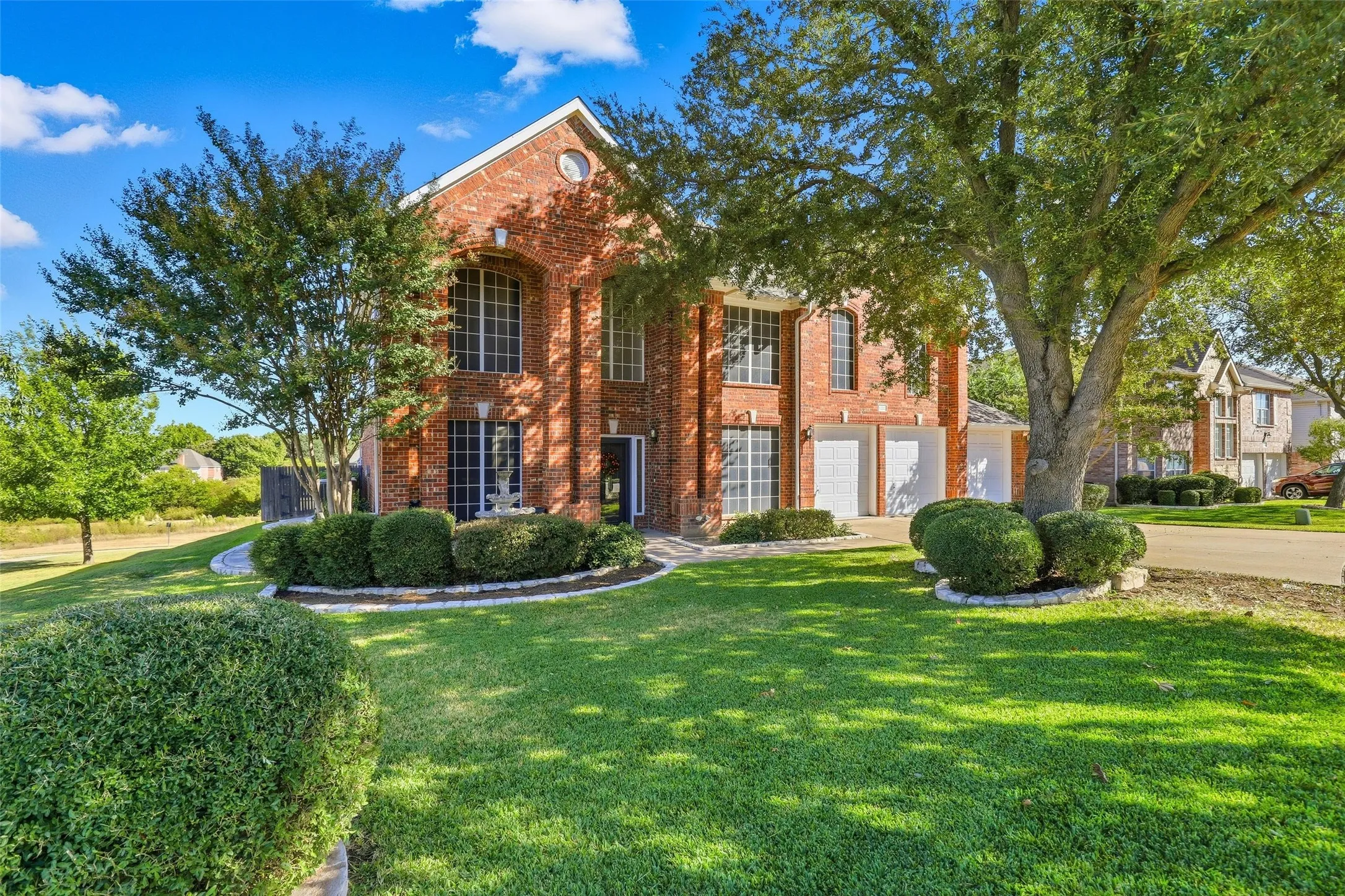 View of front of home with brick siding, a front lawn, driveway, and an attached garage
