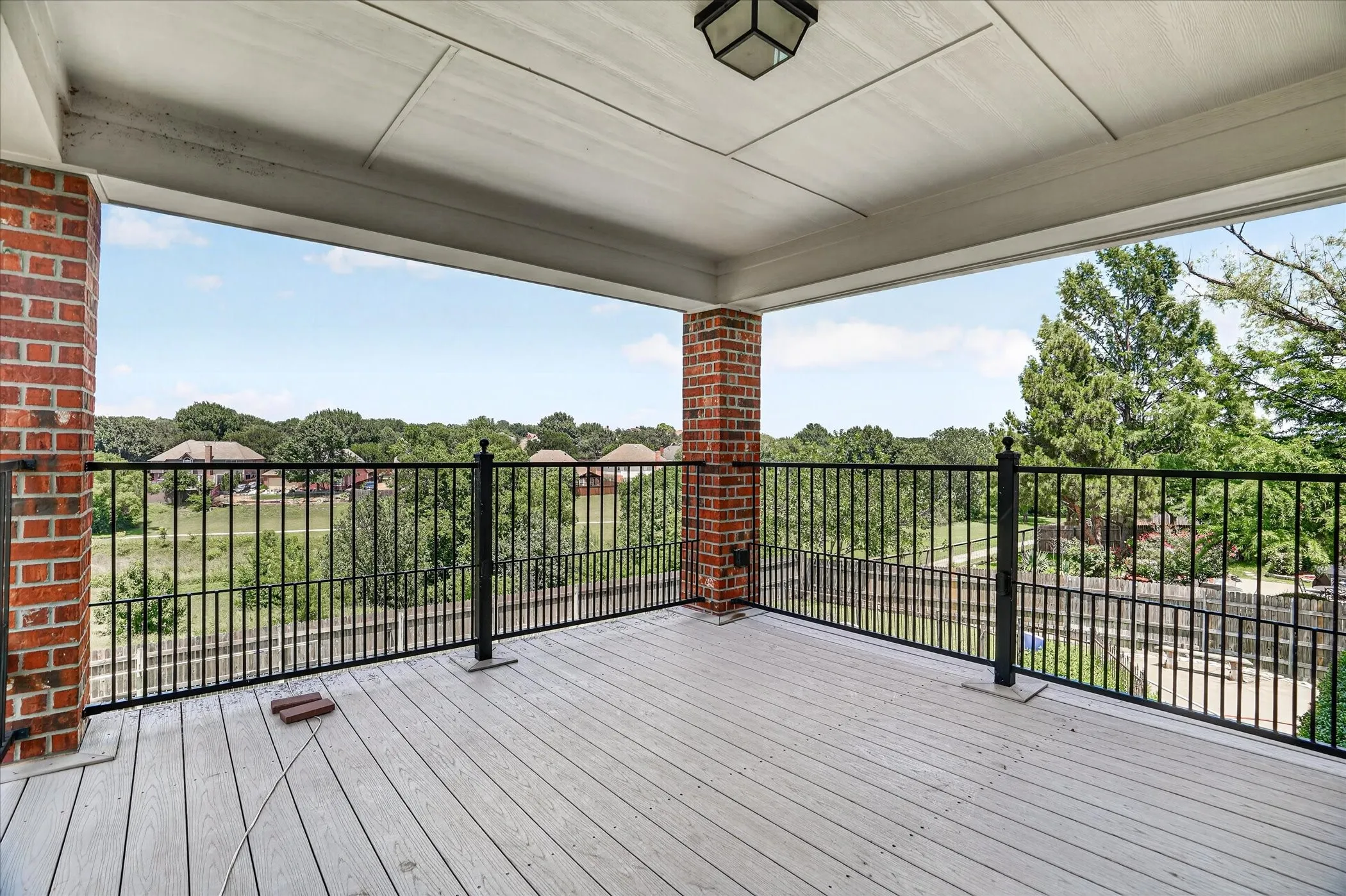 Covered outdoor balcony featuring composite decking and an open metal railing system