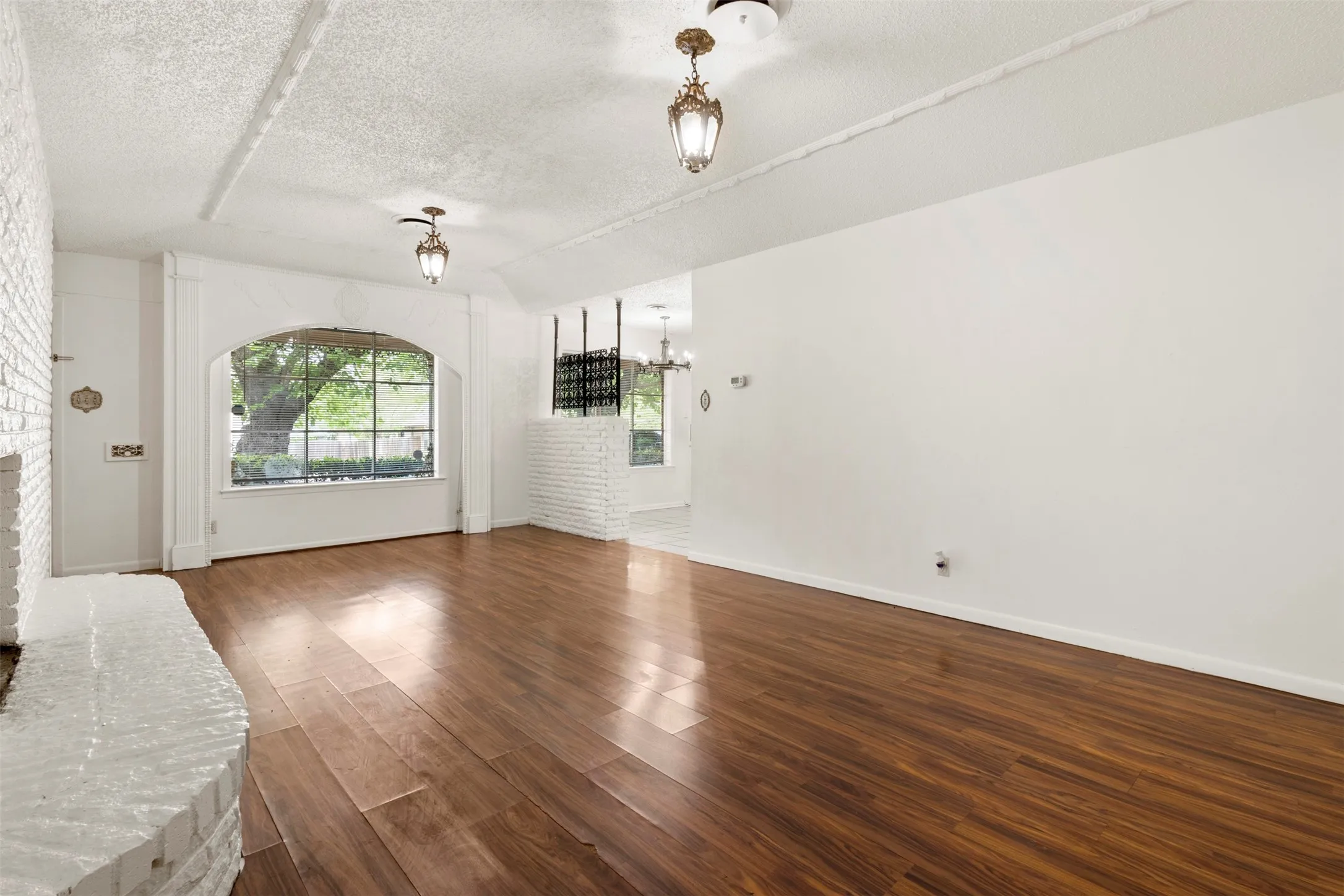 Unfurnished living room with a textured ceiling, dark wood-style flooring, and a chandelier