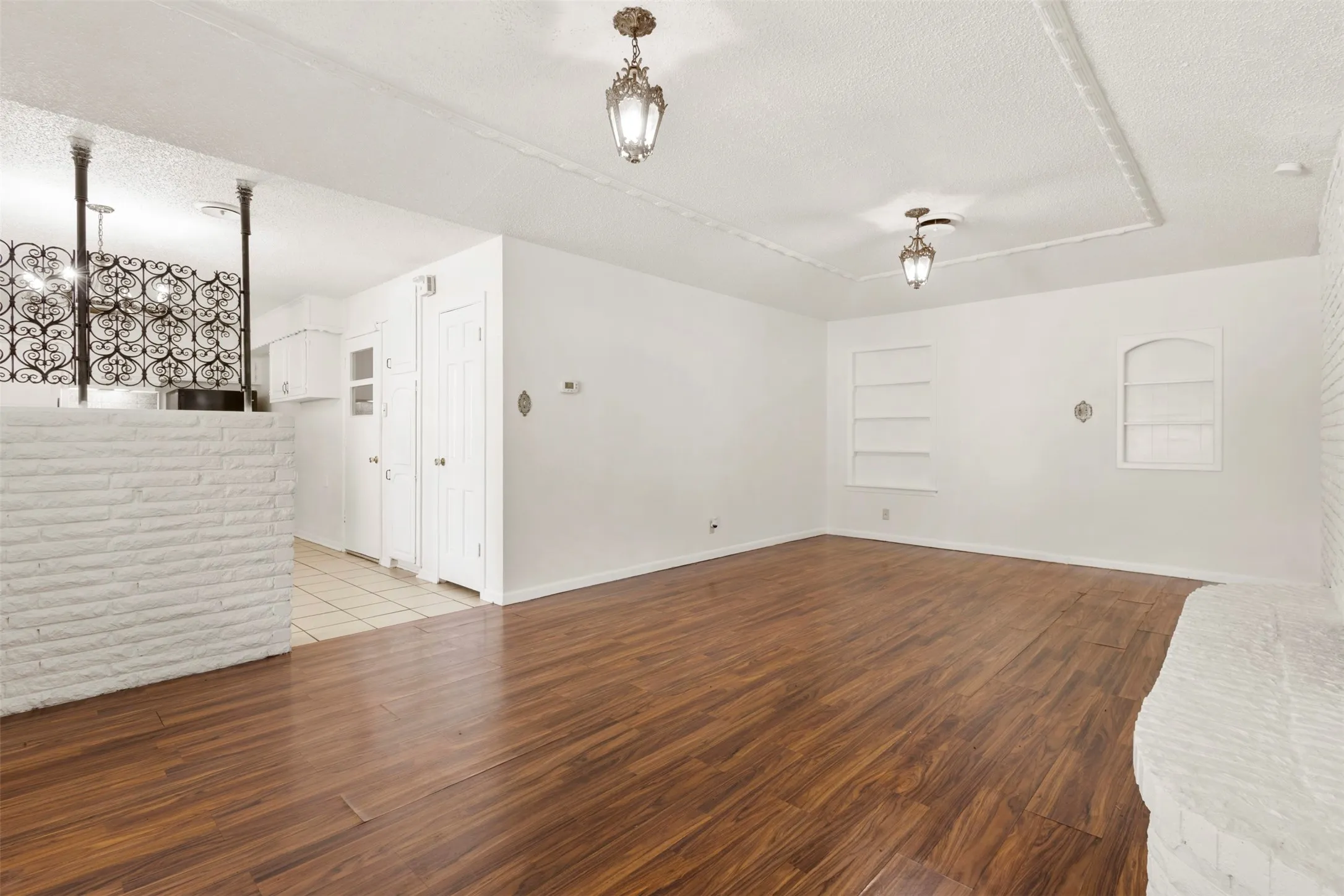 Empty room with a textured ceiling, dark wood finished floors, and built in shelves
