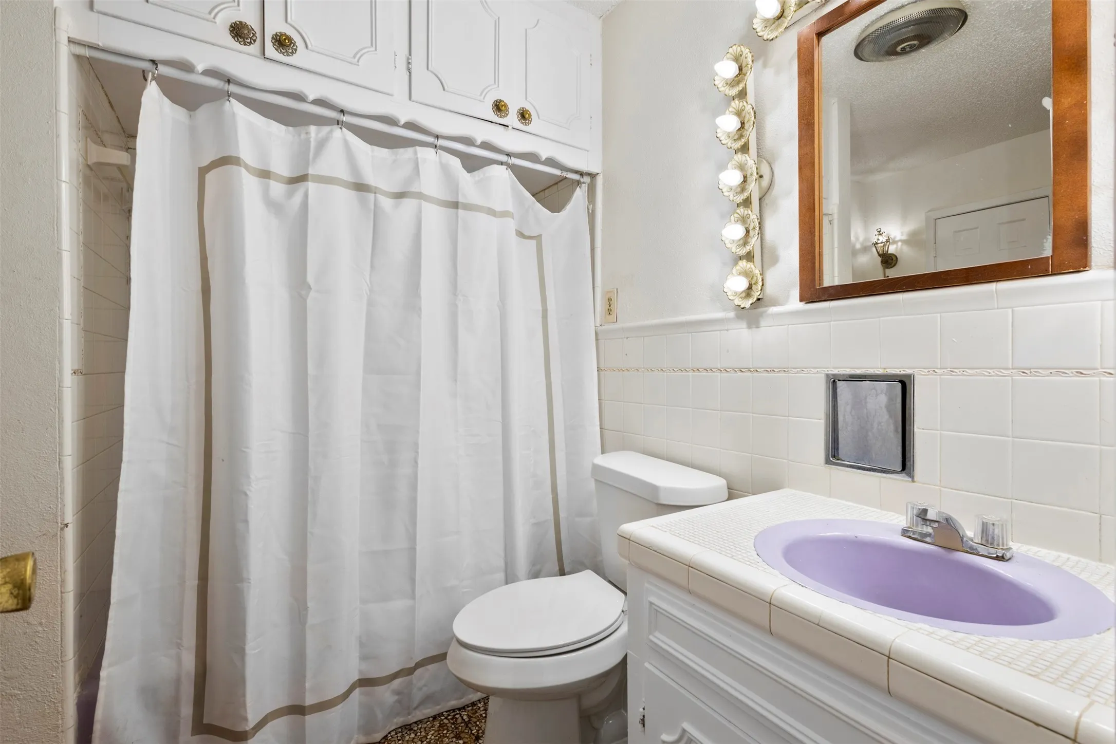 Full bathroom featuring vanity, curtained shower, and tile walls