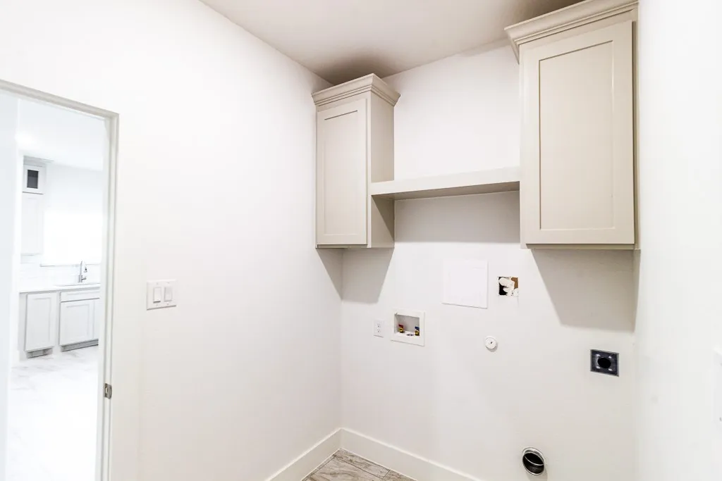 Utility room featuring custom cabinetry with ample overhead storage, open shelving, and dedicated countertop workspace