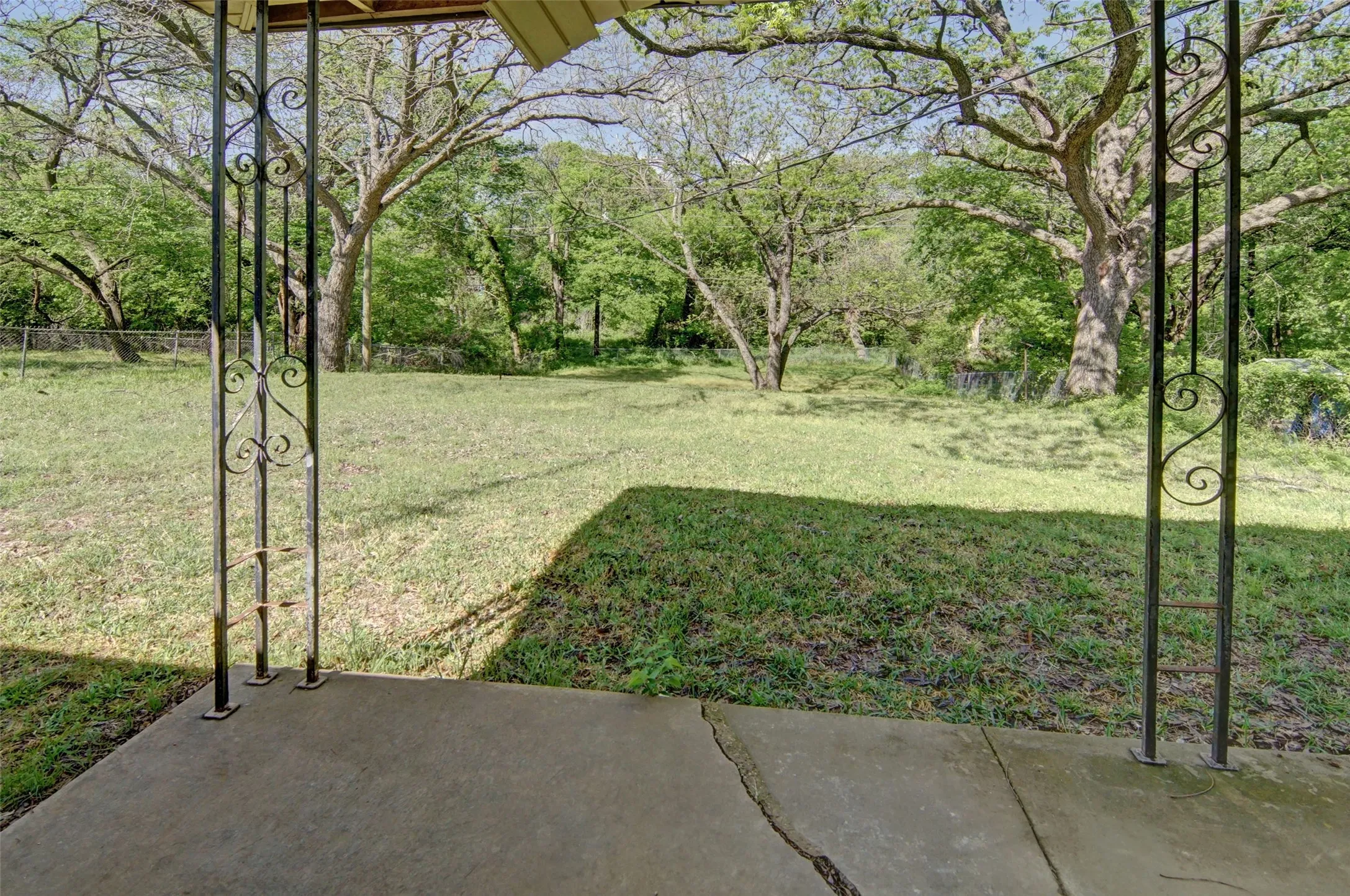 View of large backyard with lots of tall shade trees.