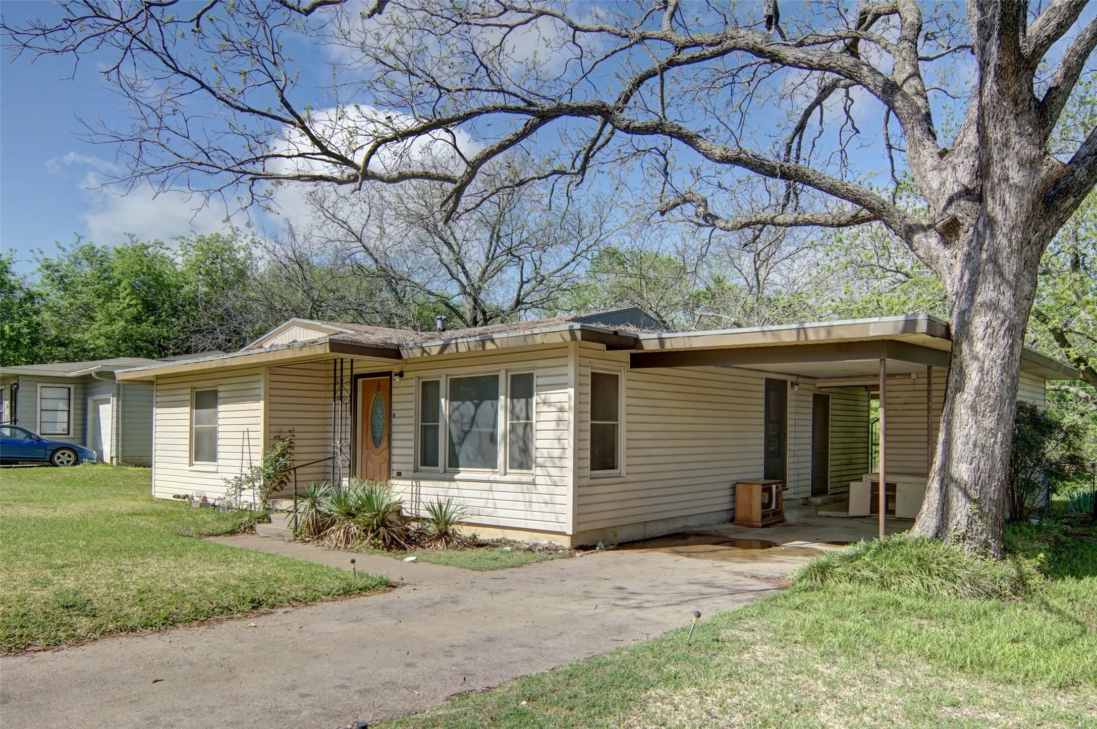 View of front facade with an attached carport, a front lawn, and concrete driveway