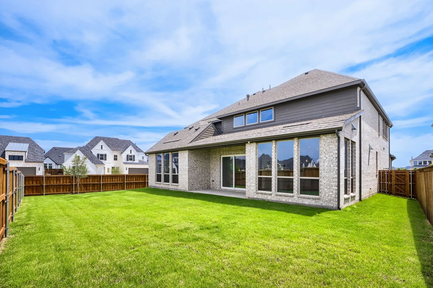 Expansive backyard featuring a lush lawn, privacy fencing, and a covered patio