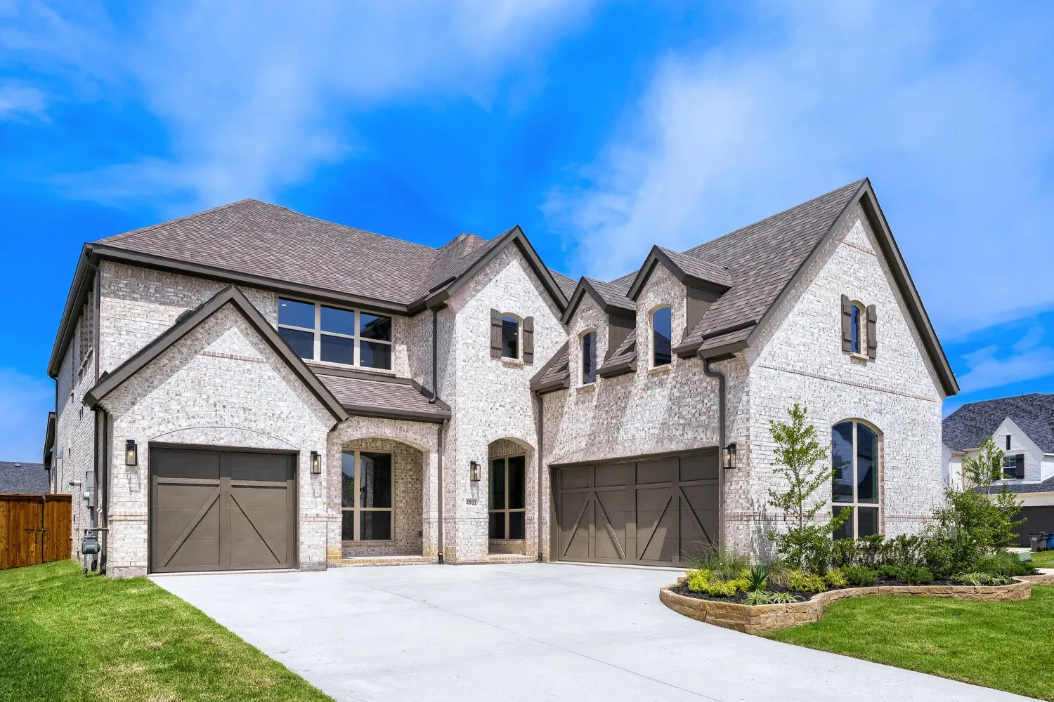 Two-story residence featuring light-colored brick exterior, dark gabled roofing, and multiple arched windows