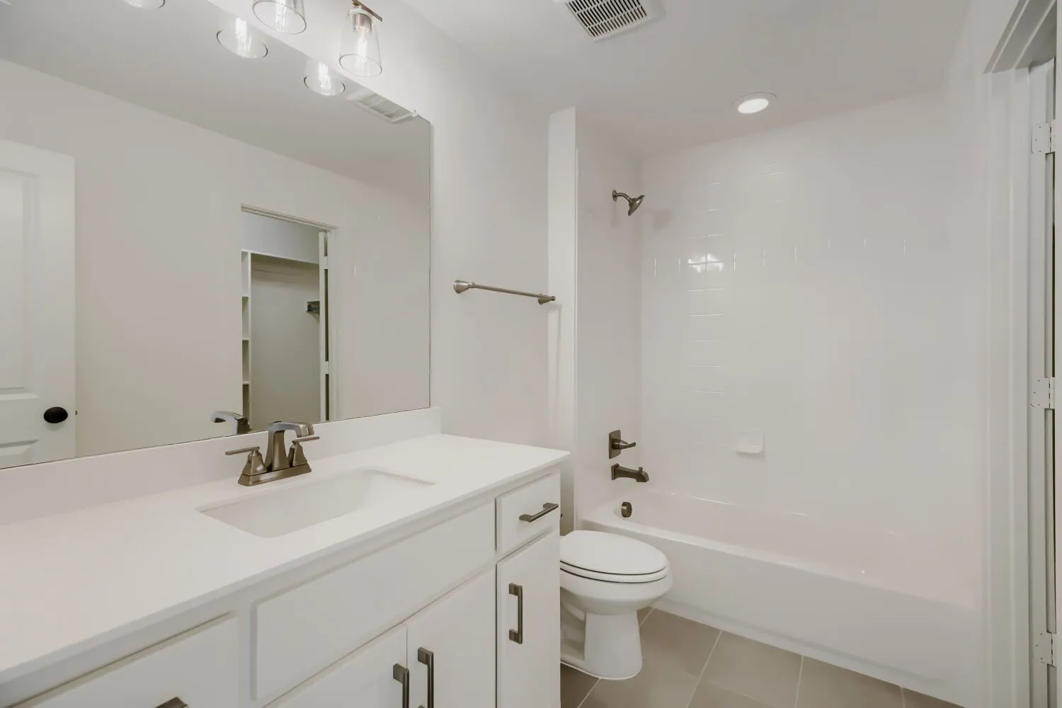 Bathroom featuring a single vanity with a white countertop, brushed nickel faucet, and white cabinetry