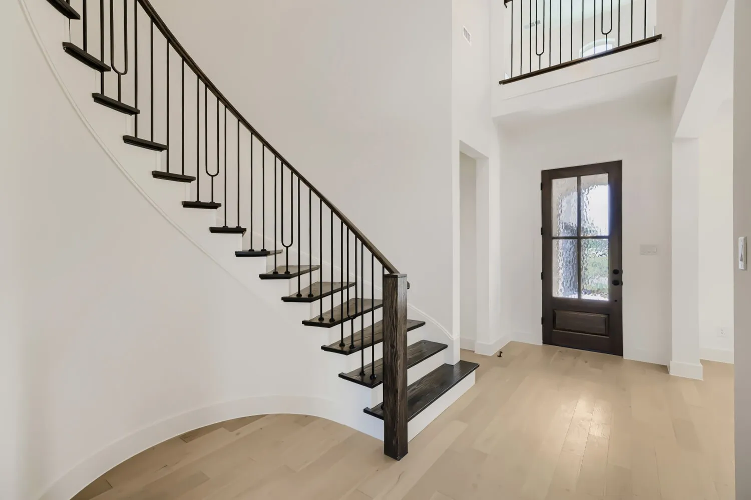 Curved staircase featuring dark wood treads and wrought iron balusters