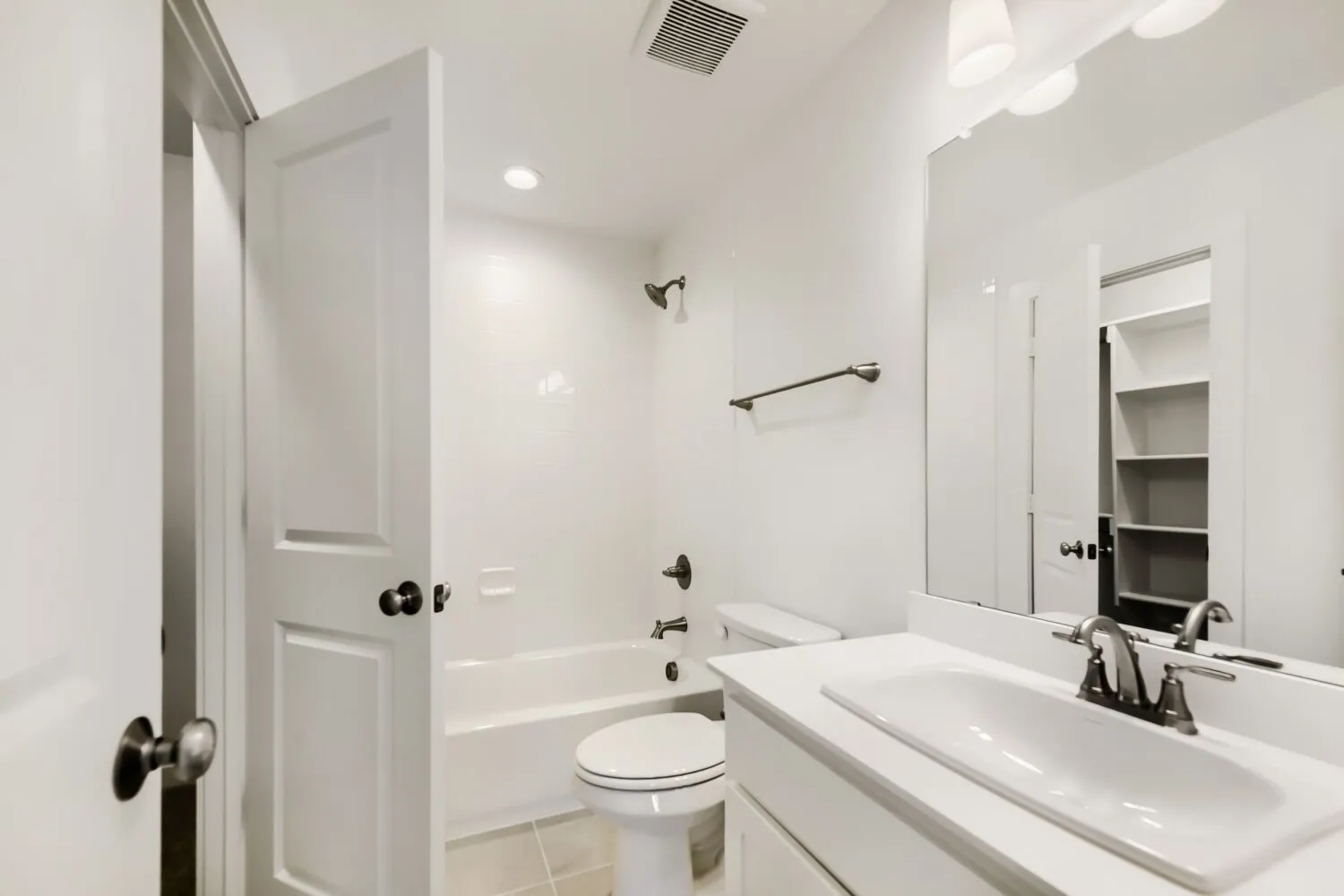 Bathroom featuring a single vanity with an integrated sink, brushed nickel faucet, and a large mirror