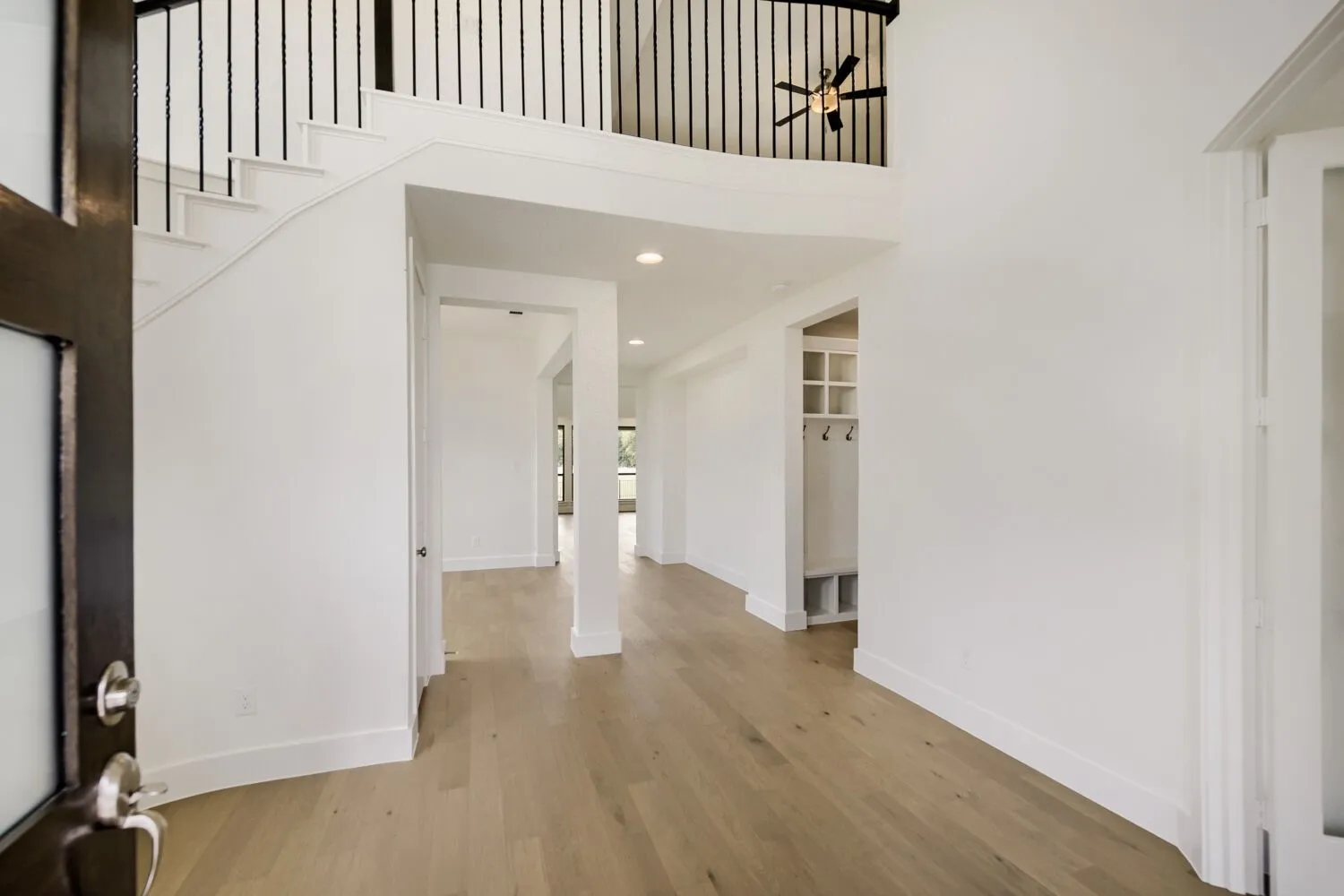 Spacious foyer with light wood-finish flooring and white baseboards